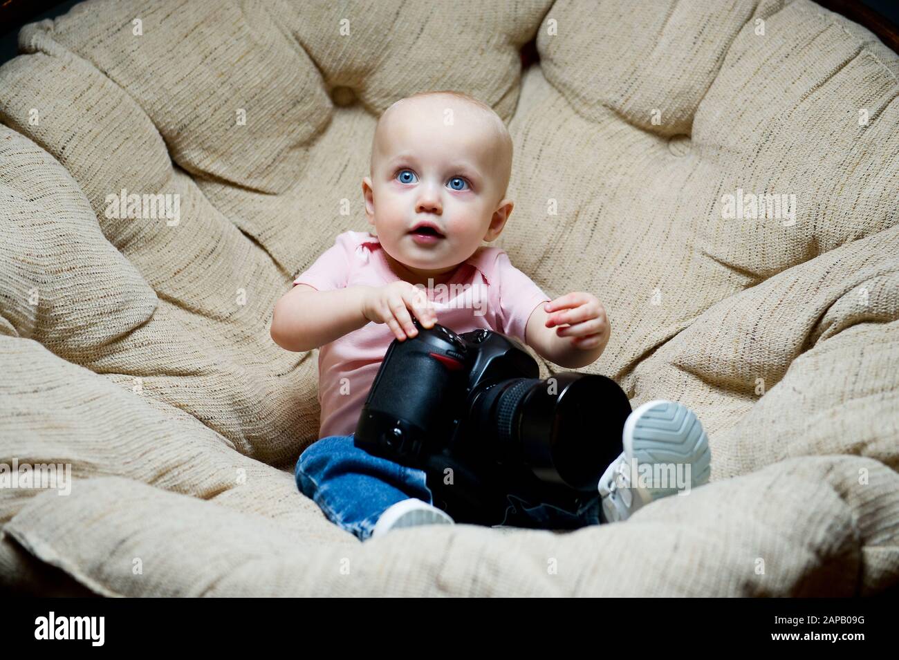bambina seduta su una grande sedia con una grande macchina fotografica Foto Stock