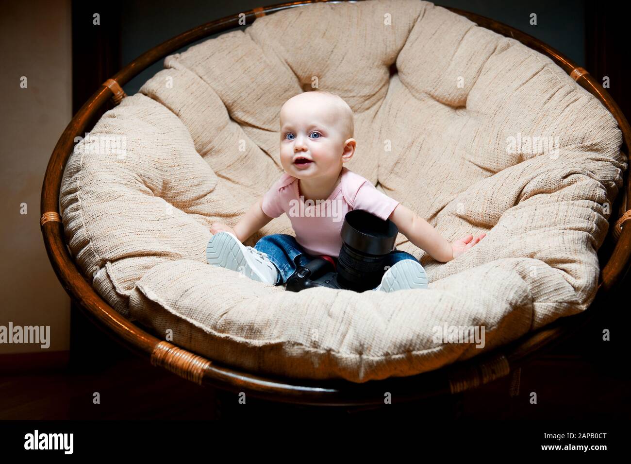 baby girl seduto su una grande sedia con una grande macchina fotografica Foto Stock