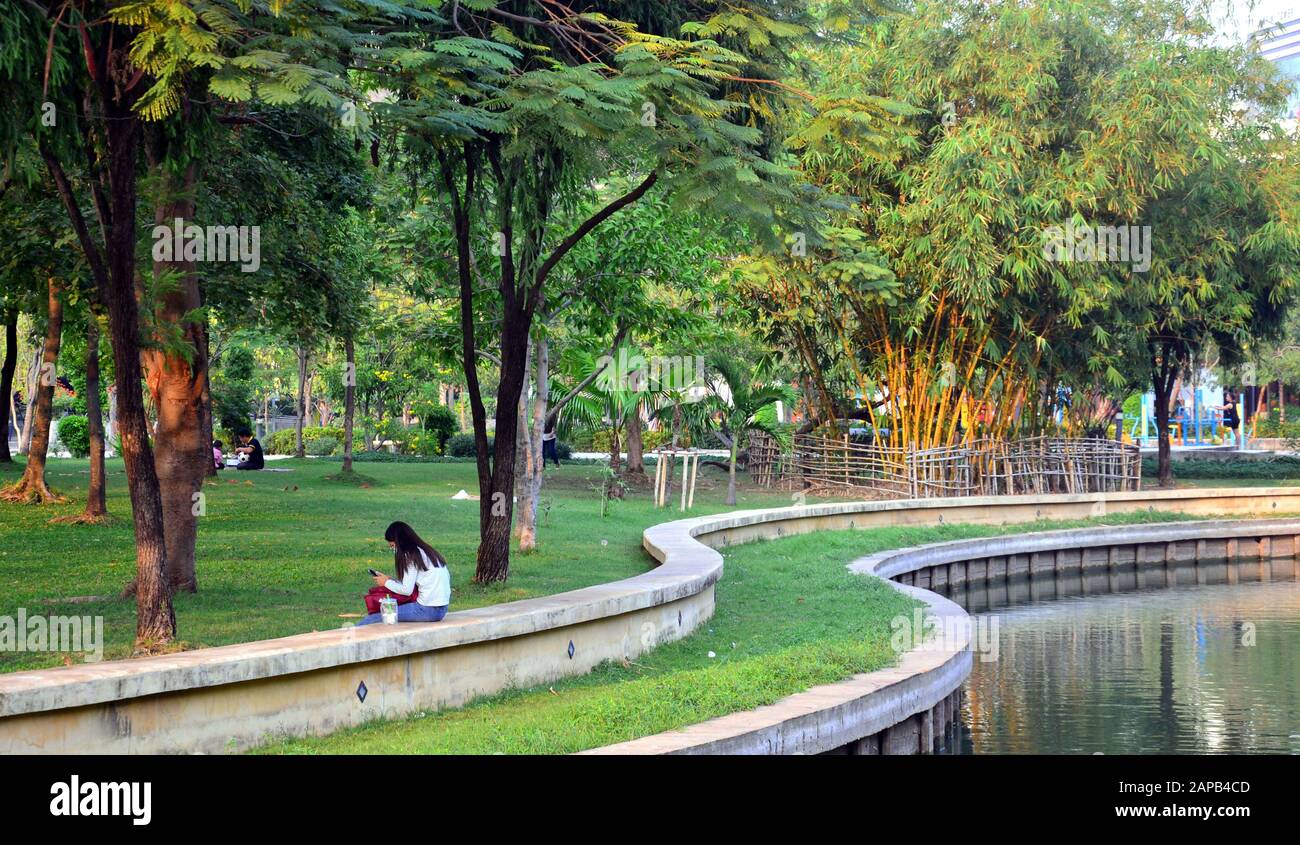 Una giovane donna siede, riposando, da sola, nel parco di Suan Plu, Bangkok, Tailandia, Asia, Foto Stock