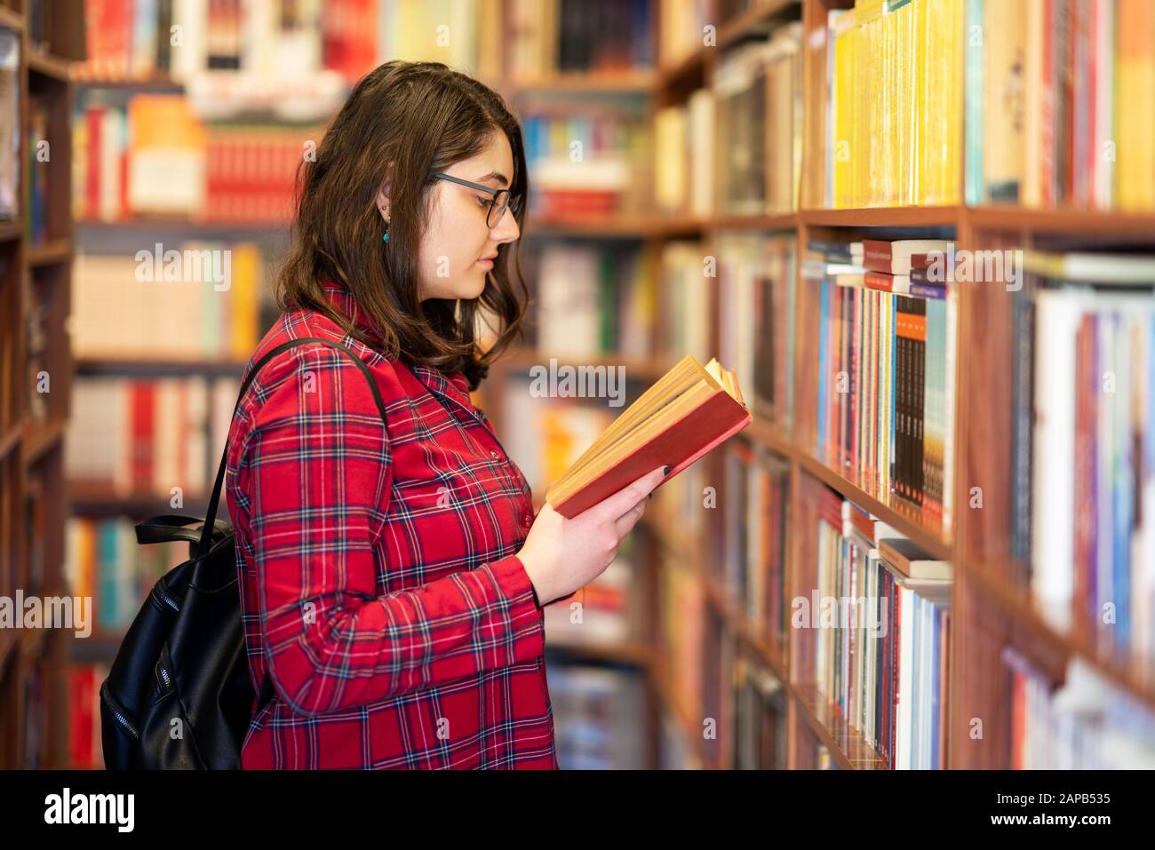 La ragazza intellettuale di Teenage sceglie i libri e li sceglie da una biblioteca o da una libreria Foto Stock