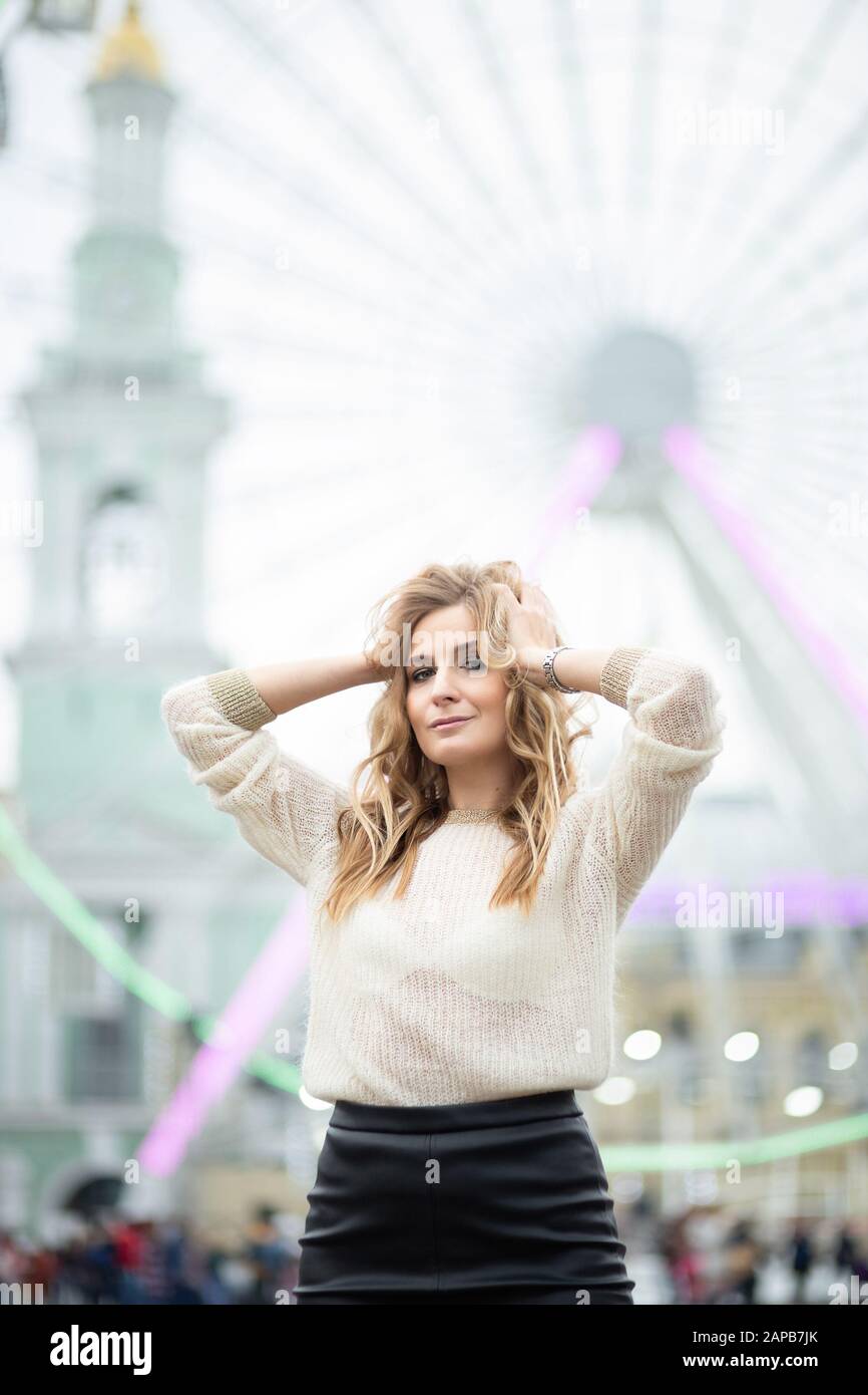 Gorgeus curly bionda donna in pelle gonna posa sul fondo ruota ferris Foto Stock