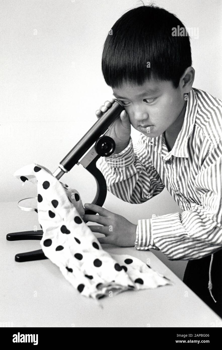 Schoolboy guardando attraverso un microscopio, scuola primaria Nottingham UK 1992 Foto Stock