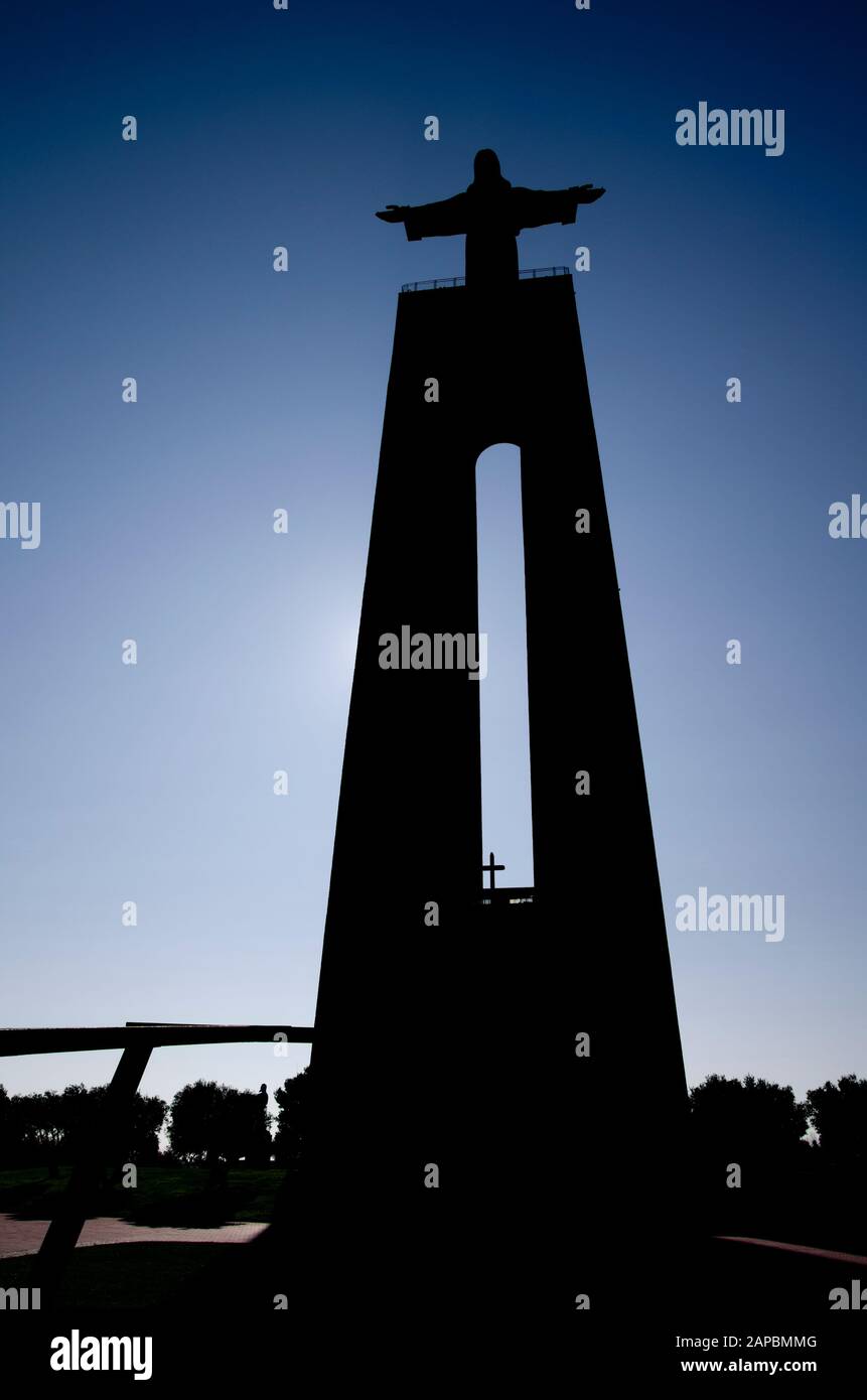 Silhoutte del Santuario Nazionale di Cristo Re ad Almada di fronte a Lisbona. Vista frontale dalla parte anteriore sotto contro un cielo blu chiaro. Portogallo. Foto Stock