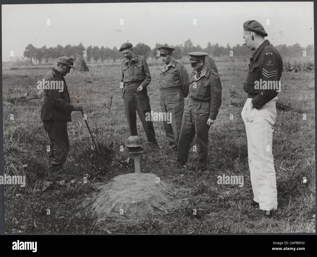 Approvvigionamento alimentare: Wageningen Descrizione: Il Servizio di identificazione e stoccaggio, eseguito dal Dr. A. van Anrooy e Dr. A.H. Croes, scavare i corpi di persone che sono morte a seguito di bombardamenti da parte dei tedeschi a Eindhoven, e che sono stati sepolti in fretta lungo le strade o in pascoli. Dopo di che, la r Annotation: Sembra che questa sia una tomba di un soldato tedesco. A sinistra è un soldato tedesco con un bastone (sminamento?) Data: 1 gennaio 1945 Parole Chiave: Scavo di massa, scavi Foto Stock