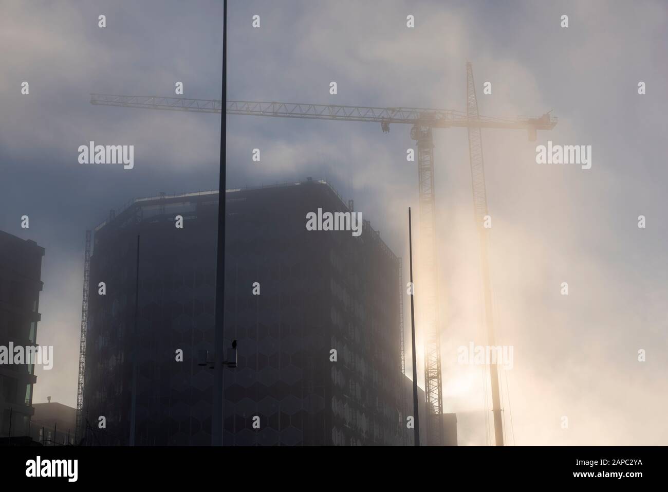 Taglio leggero attraverso la nebbia durante la costruzione di un nuovo edificio in Centenary Square Birmingham, West Midlands Inghilterra UK Foto Stock
