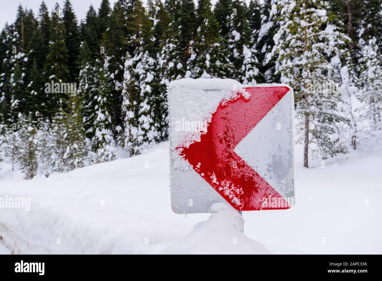 Segnali stradali che avvisano i conducenti della curva pericolosa in avanti in inverno Foto Stock
