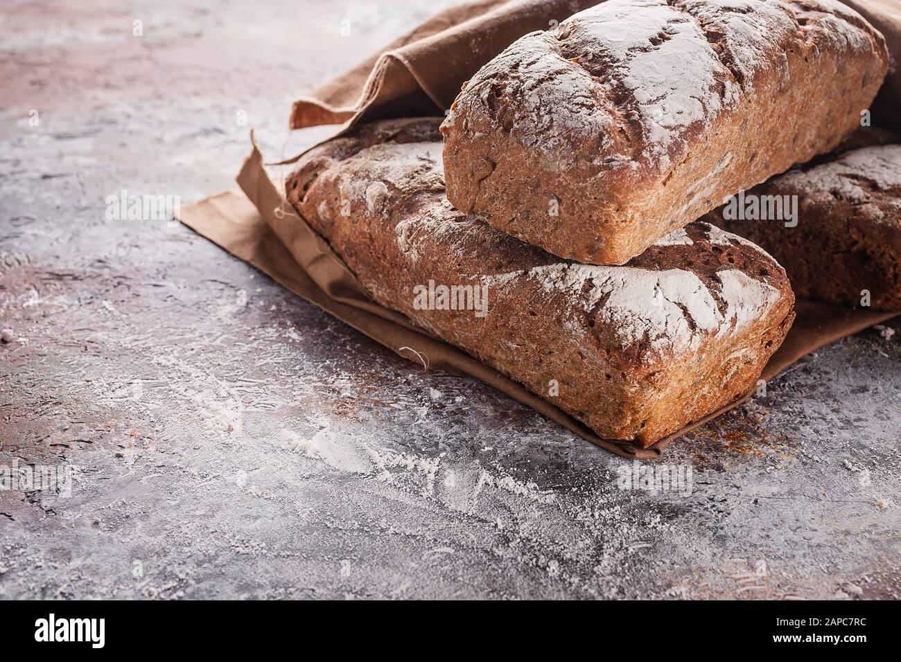 Pane di farina di segale appena sfornato con semi di girasole e zucca su un tovagliolo marrone. Foto Stock