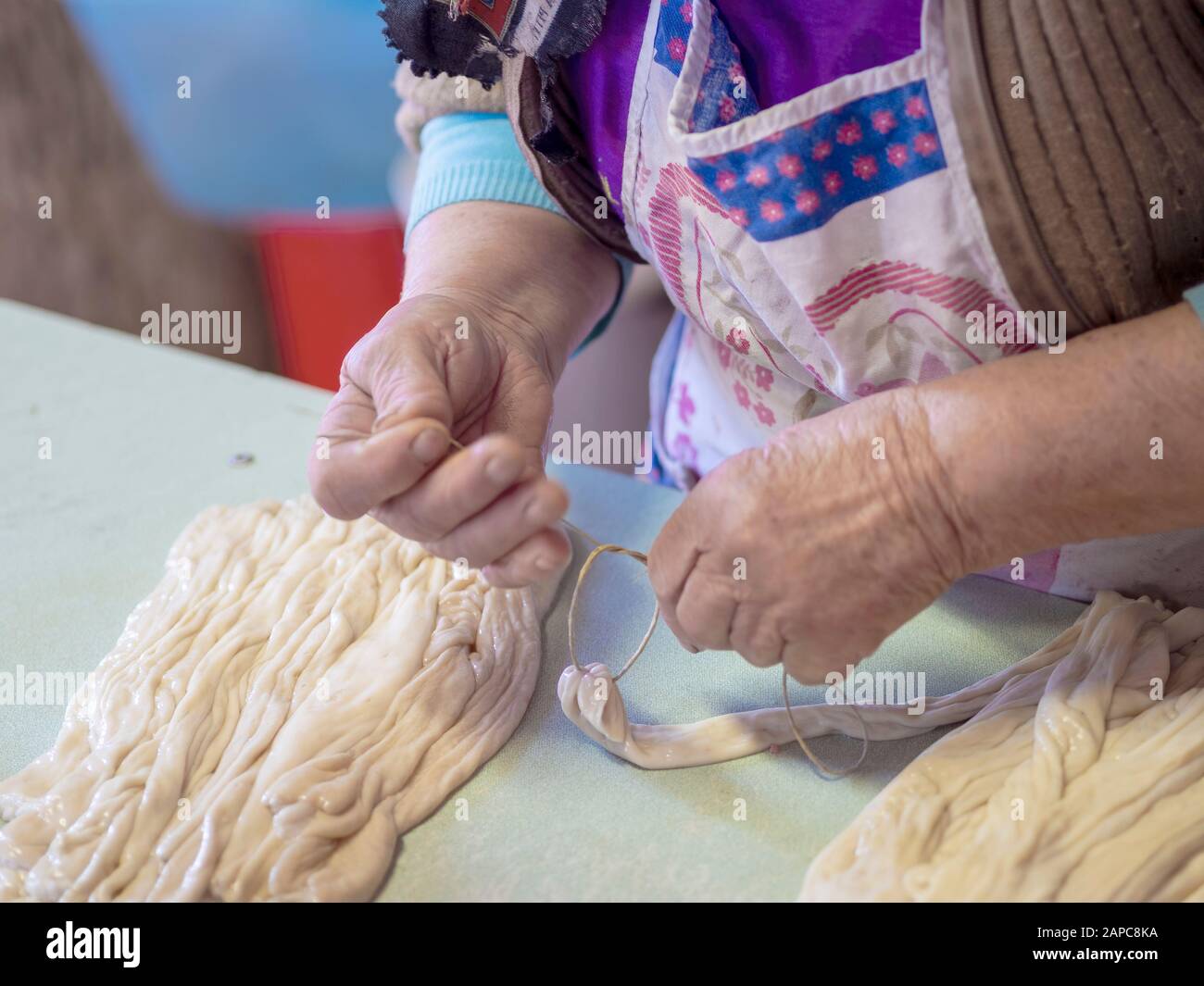 Donna che fa le pelli tradizionali della salsiccia di maiale usando gli intestini del maiale. Rustico, rurale Italia. Produzione agricola genuina. Foto Stock