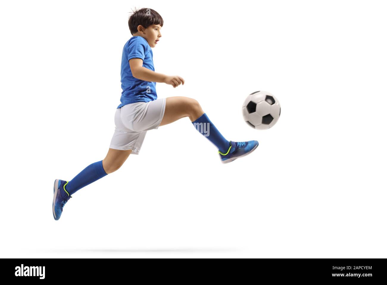 Profilo a tutta lunghezza di un ragazzo che salta e calcia una palla da calcio isolato su sfondo bianco Foto Stock