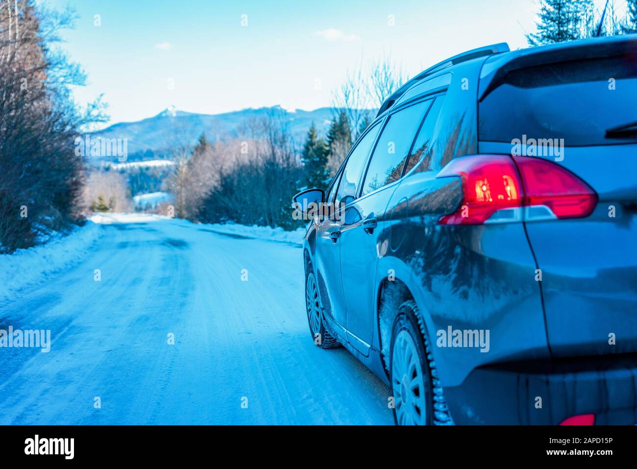 Auto su strada innevata di montagna. Concetto di viaggio su sci, vacanze invernali. Vista posteriore della vettura. Montagna sullo sfondo Foto Stock