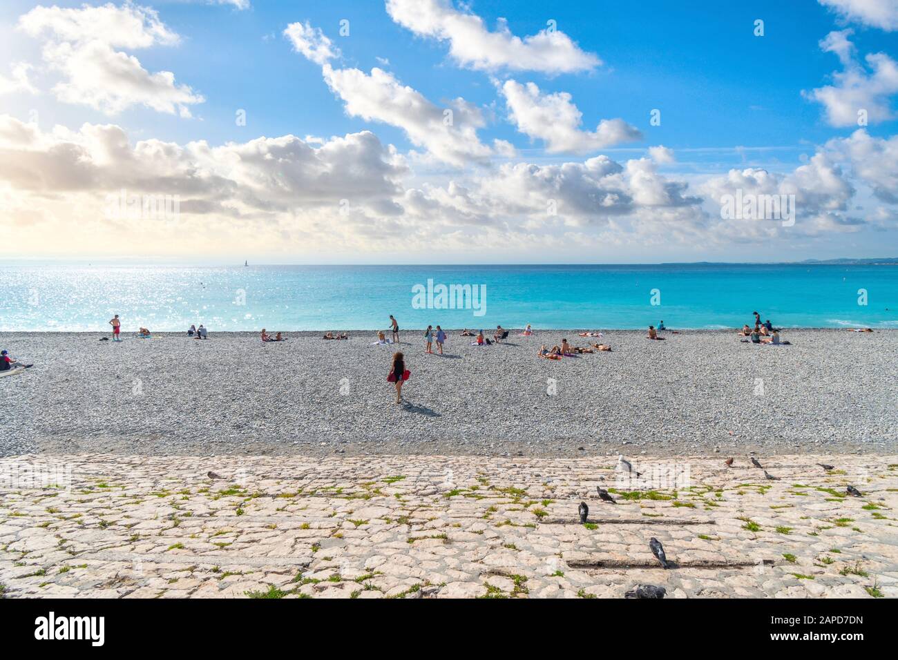 I turisti si rilassano sulla spiaggia di ciottoli nella Baia degli Angeli sulla Riviera Francese a Nizza, Francia. Foto Stock