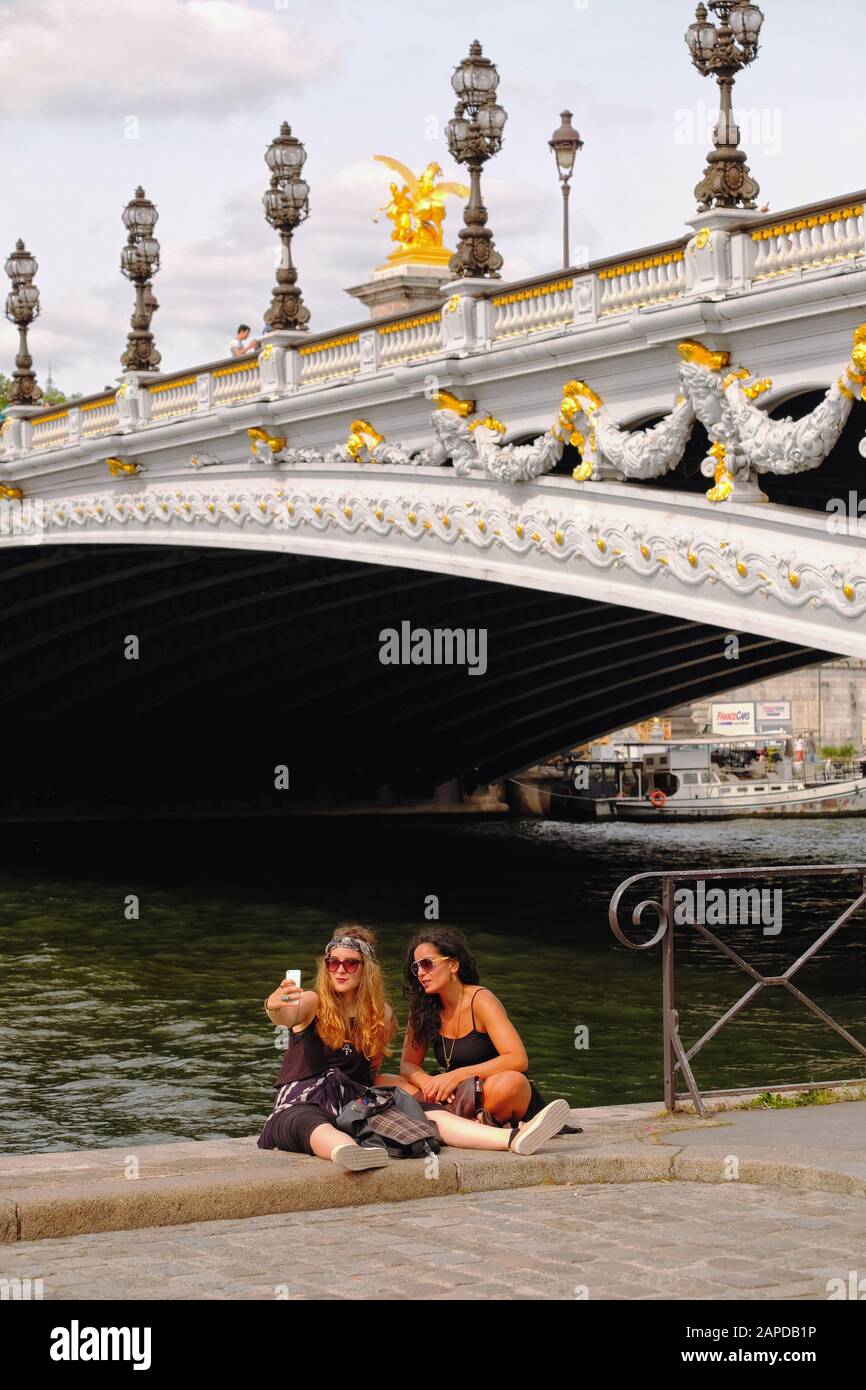Due donne fanno un selfie sul fiume Senna con il ponte più ornato di Parigi Pont Alexandre III come sfondo glamour Foto Stock