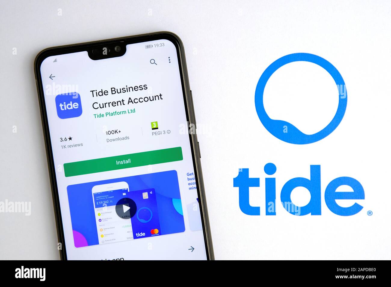 L'app corrente di TIDE Business in Play Market sullo schermo dello smartphone, che si trova accanto al logo sulla brochure cartacea. Foto Stock