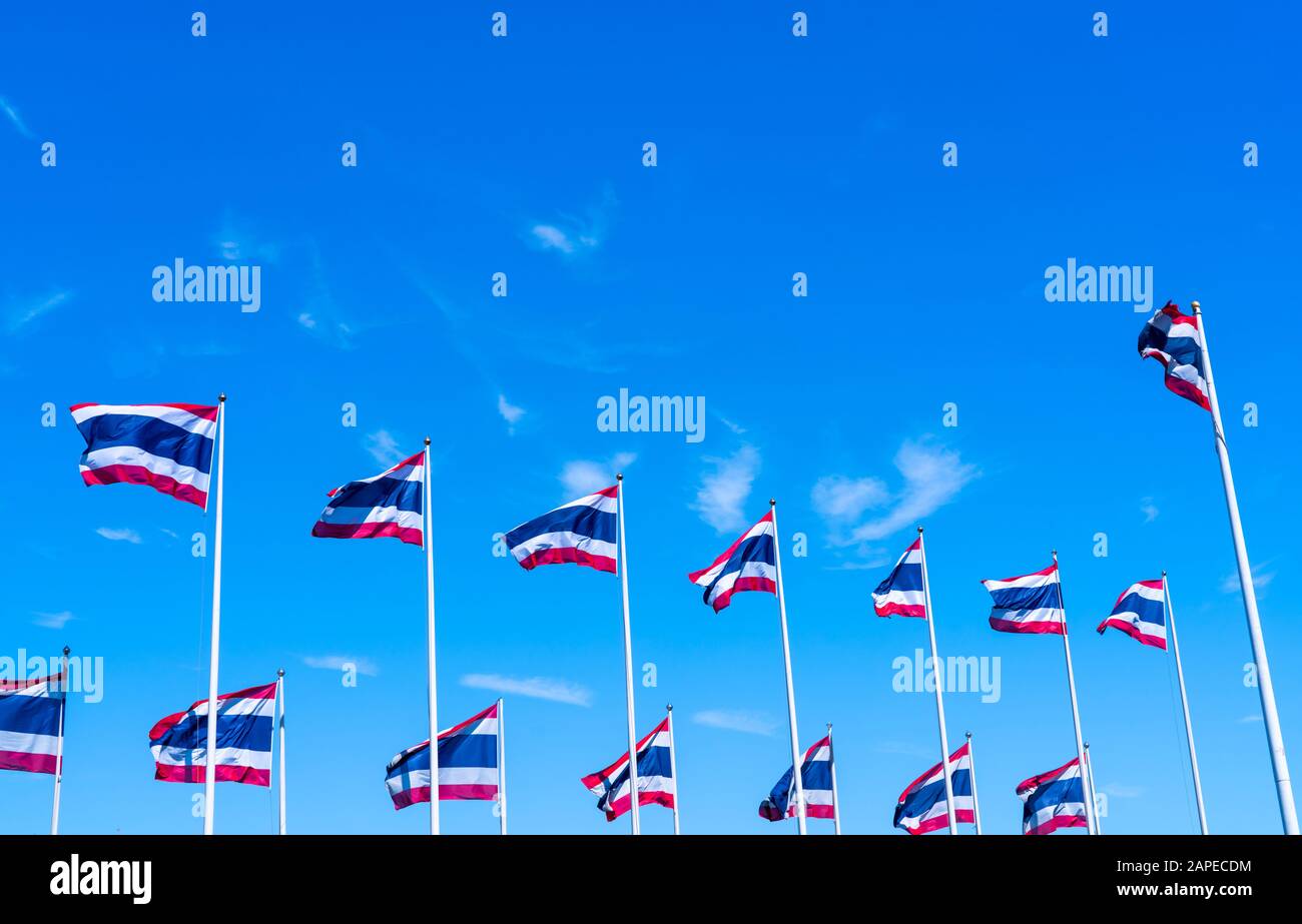 Molti di Thailandia bandiera sventolare in cima a flagpole contro il cielo blu. Bandiera tailandese è stata disegnata in cima al flagpole. Rettangolo di colore rosso, blu e bianco Foto Stock