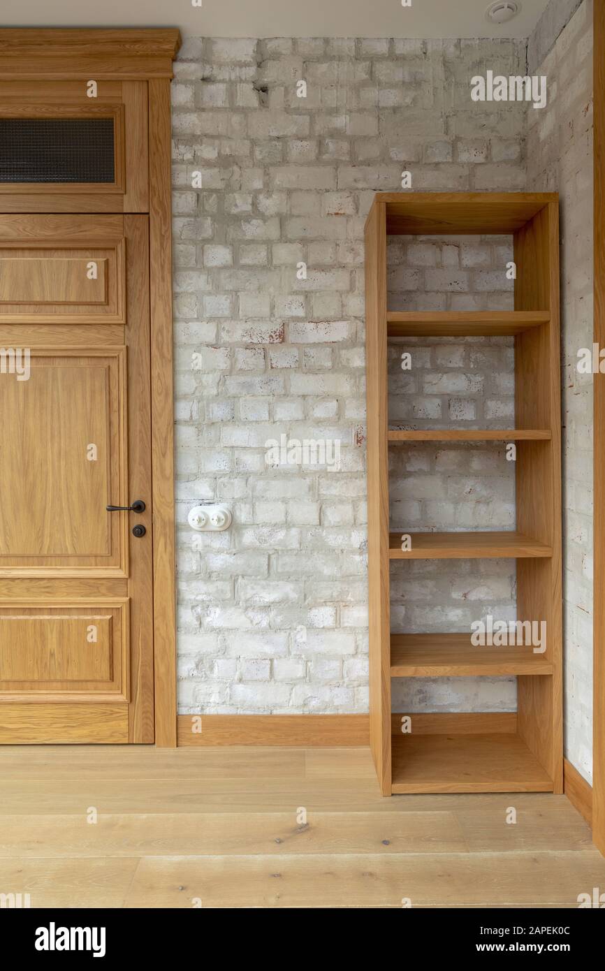Porta di quercia e libreria contro muro di mattoni bianchi Foto Stock