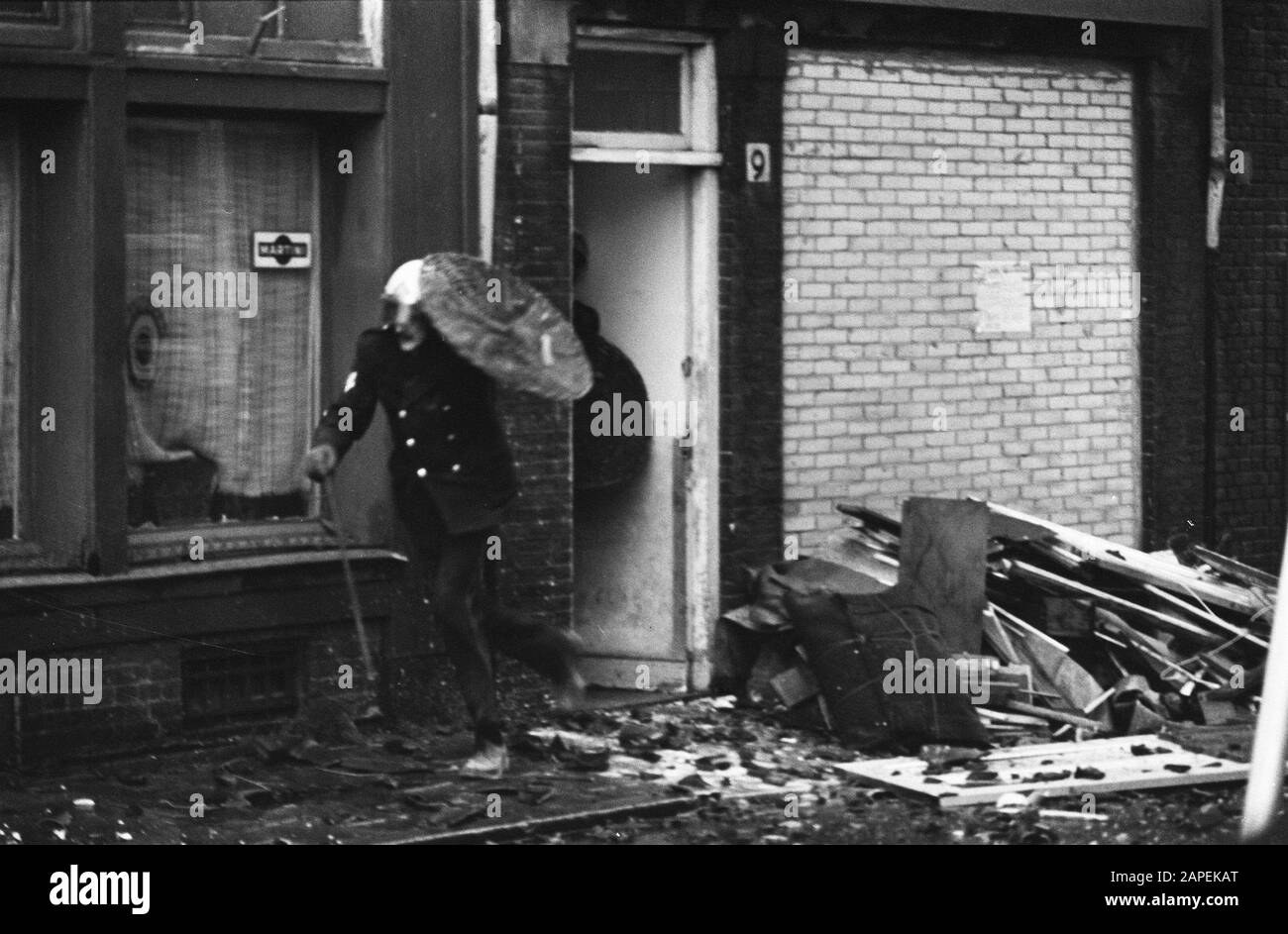 Residenti Nieuwmarktbuurt Amsterdam resistere alla demolizione di case per metrobuilding; poliziotto si protegge con scudo contro le pietre Data: 12 dicembre 1974 Località: Amsterdam, Noord-Holland Parole Chiave: Case, Demolition, metros, polizia Foto Stock