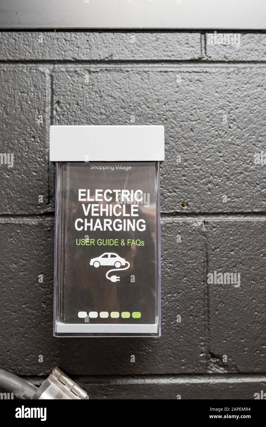 Un piccolo portadpliant montato a parete con volantini sulla ricarica di veicoli elettrici a Sydney, Australia Foto Stock
