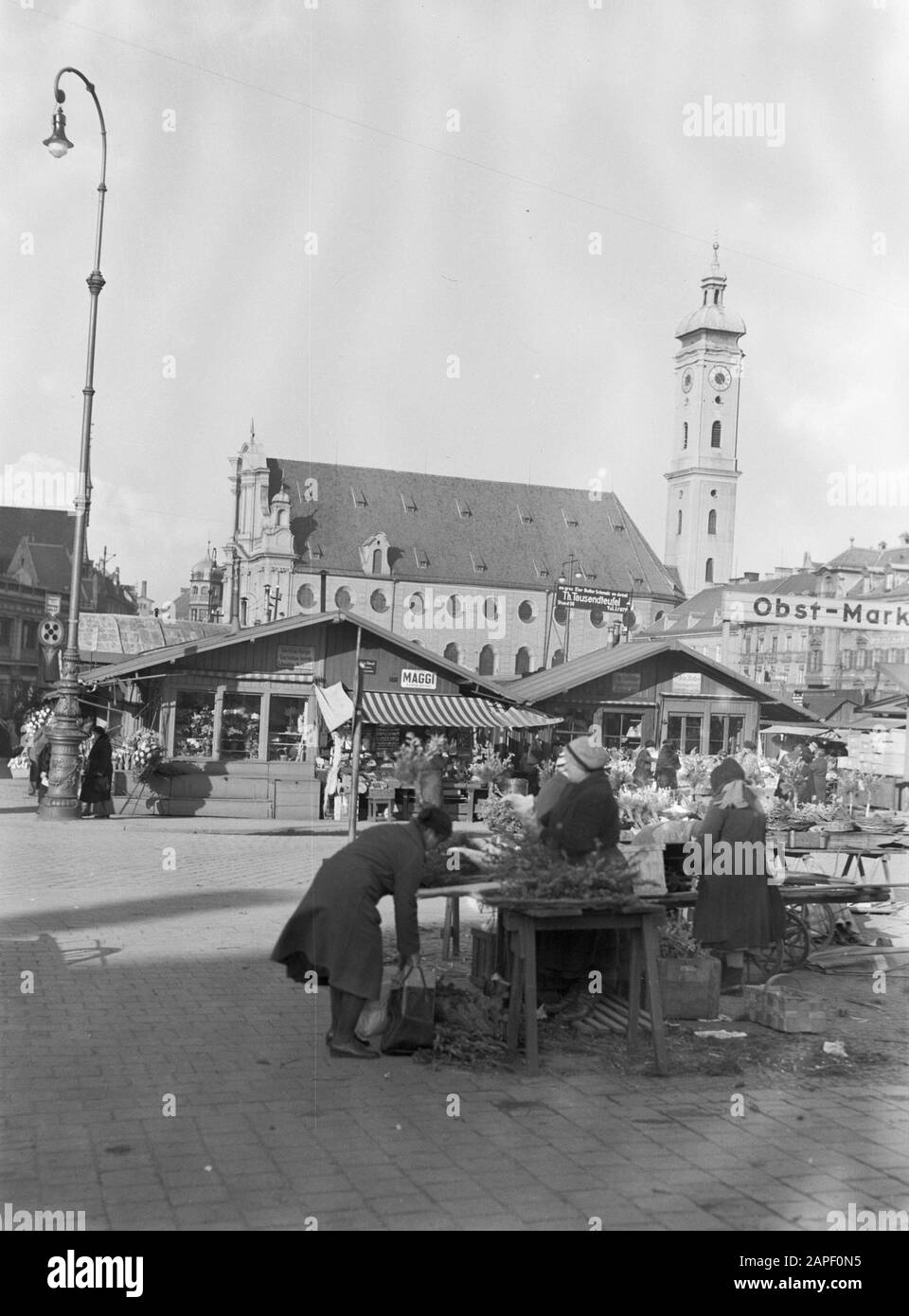 Visita a Monaco Descrizione: Mercato dei fiori con in background il Sacro Geista Kirche Data: Marzo 1935 posizione: Germania, Monaco Di Baviera Parole Chiave: Barocco, bancarelle di fiori, torri della chiesa, mercati, piazze Foto Stock