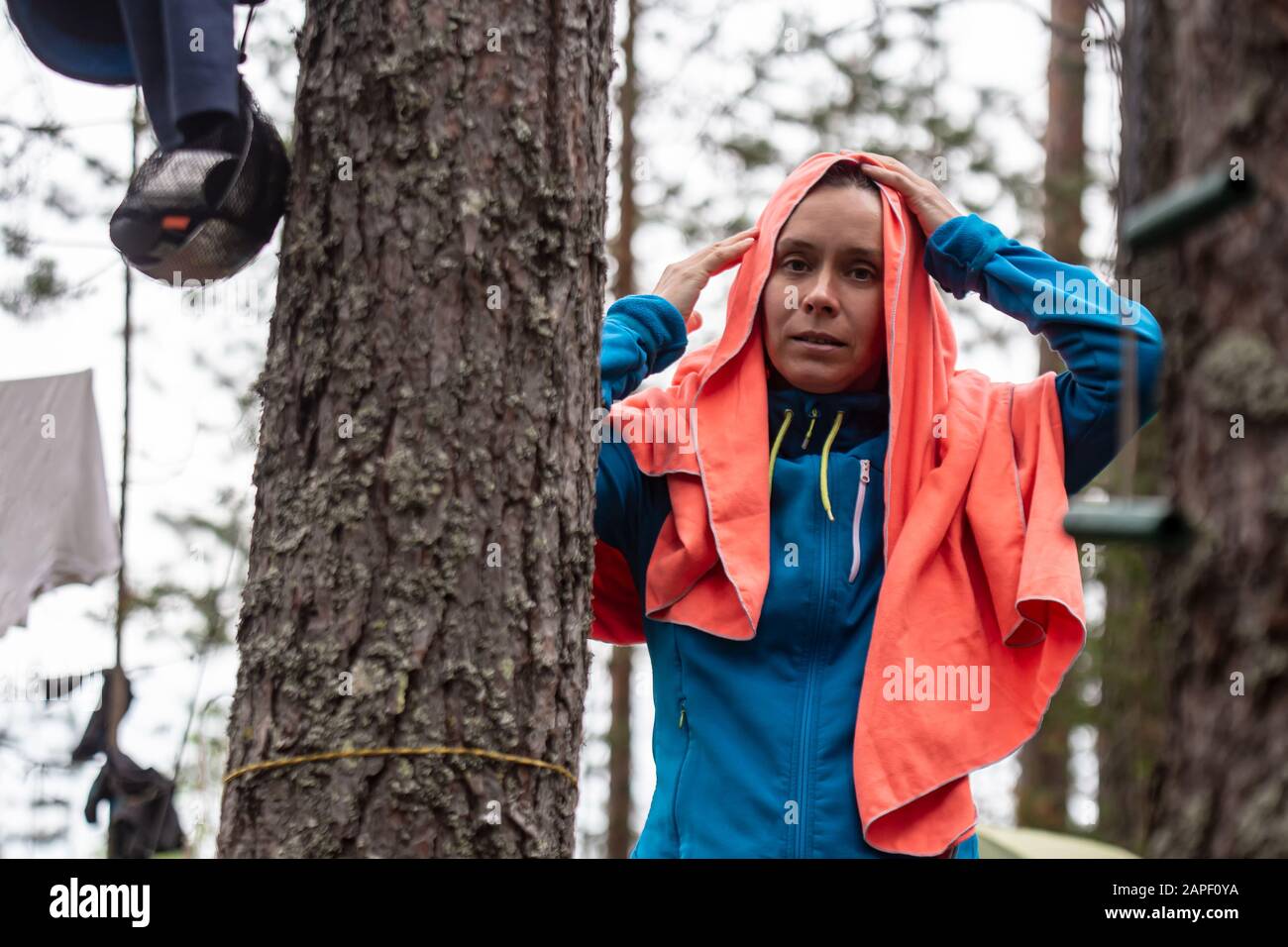 Donna con capelli bagnati, dopo aver nuotato nel lago, asciuga la testa con un asciugamano, nella foresta, nel campo, in una giornata estiva. Foto Stock