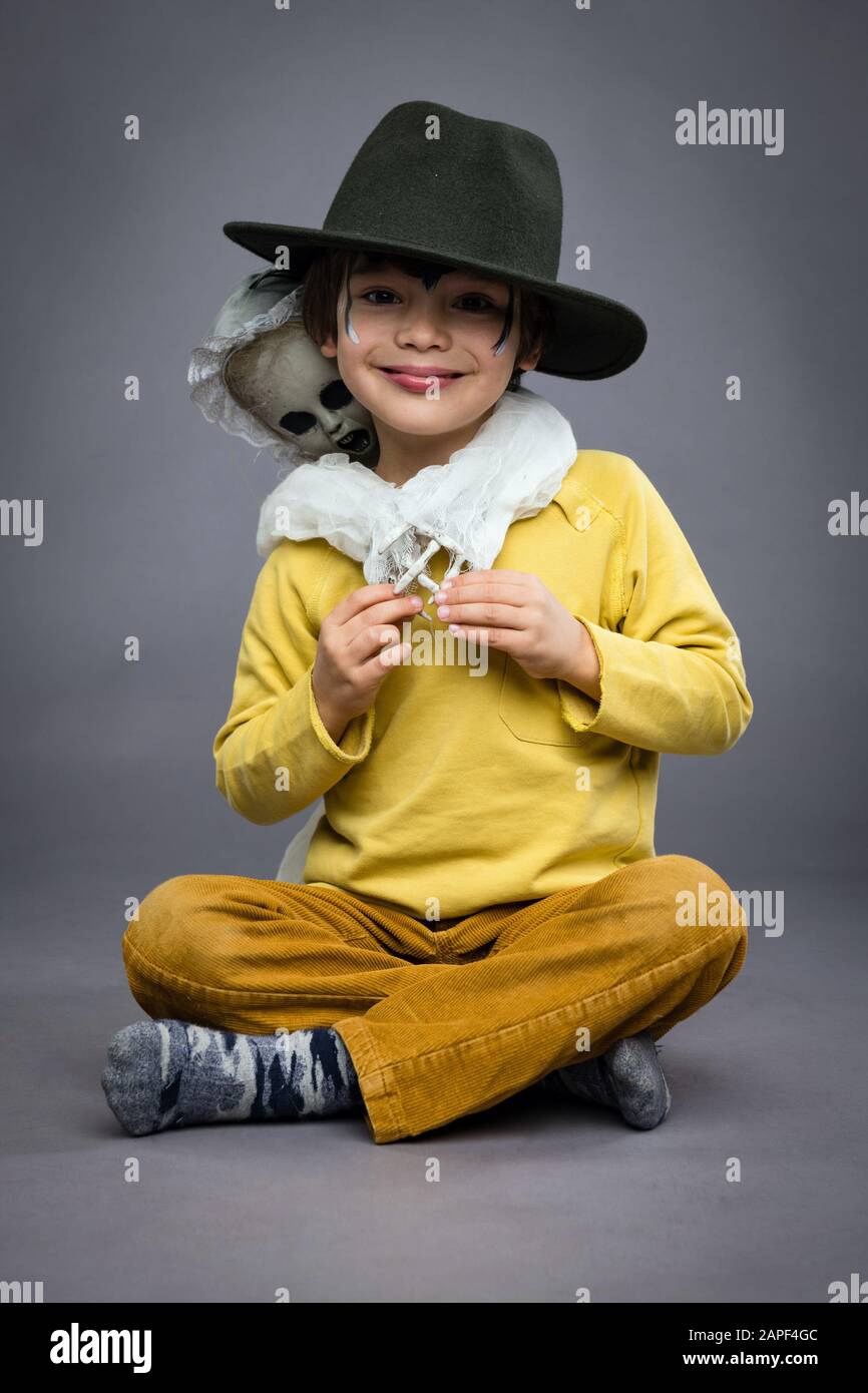 Allegro ragazzino in un cappello tiene uno scosso, sfondo grigio. Festa di Halloween Foto Stock
