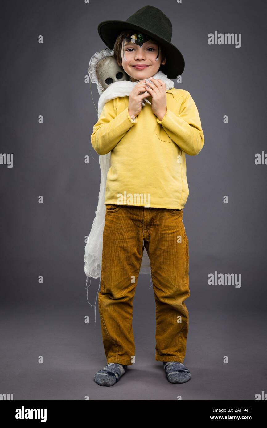 Allegro ragazzino in un cappello tiene uno scosso, sfondo grigio. Festa di Halloween Foto Stock