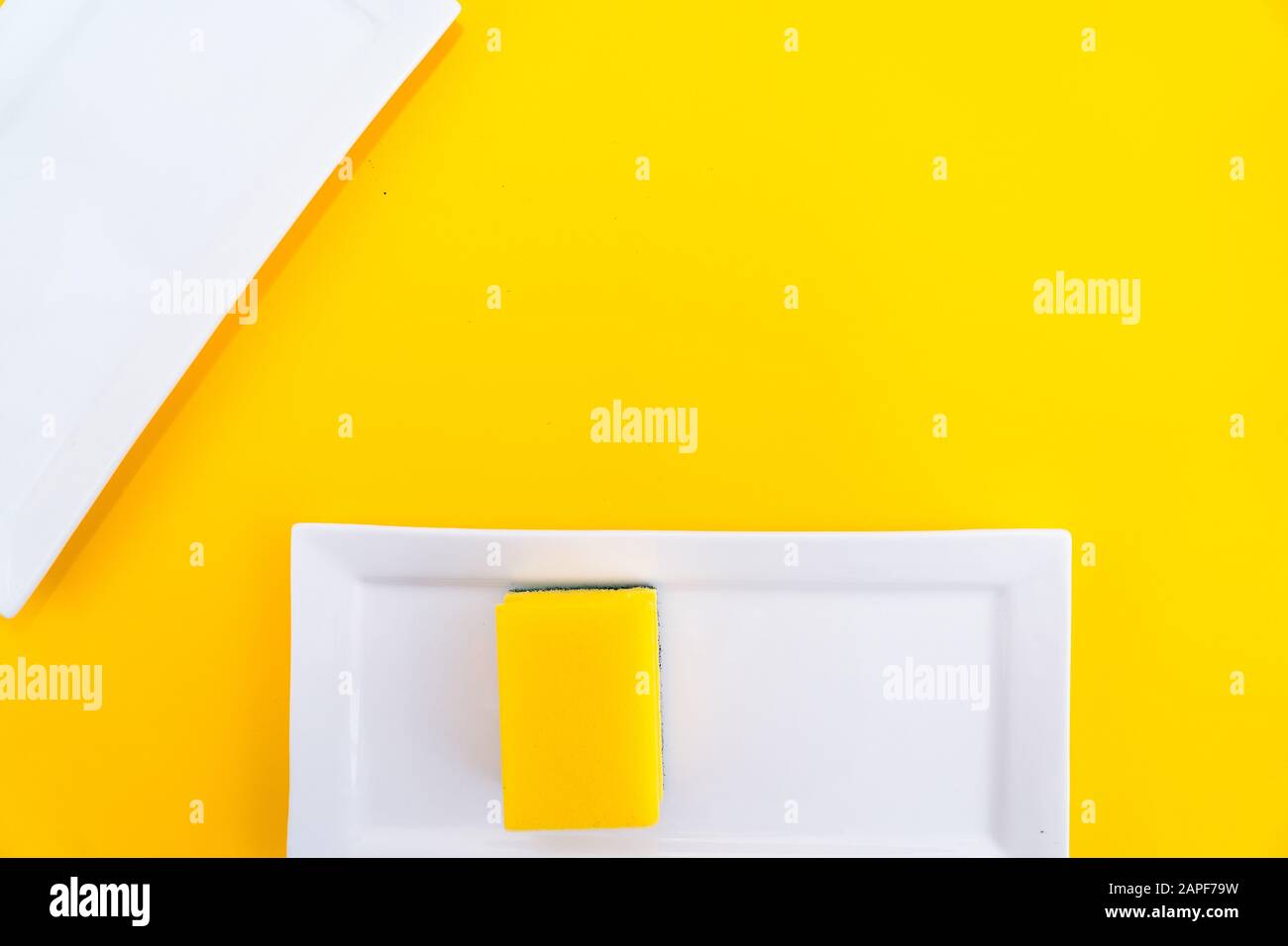 Spugna gialla per uso domestico pulente con piastra bianca su fondo giallo. Gruppo di spugne colorate luminose per piatti di lavaggio. Attrezzatura di pulizia per k Foto Stock