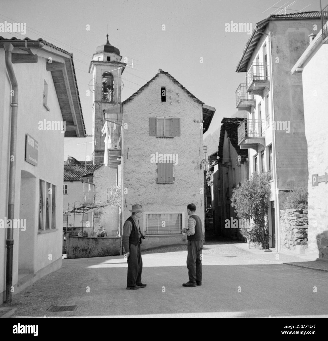 Tour lungo il lato svizzero del Lago maggiore Descrizione: Brione: Due uomini sulla piazza di fronte ad una chiesa Data: Novembre 1961 luogo: Brione sopra Minusio, Svizzera Parole Chiave: Villaggi, villaggi, edifici di chiesa, persone, piazze Foto Stock