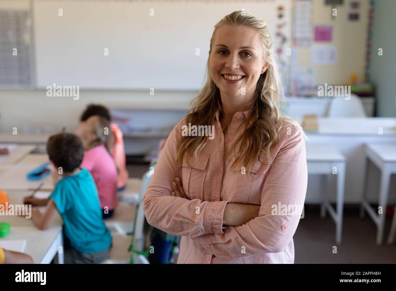 Insegnante femminile con capelli biondi lunghi in piedi in classe Foto Stock