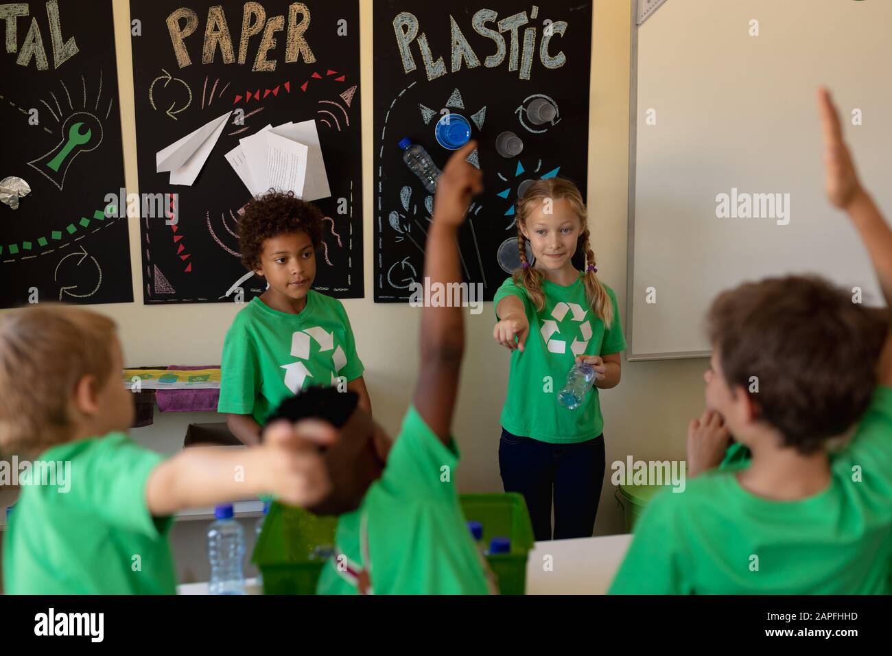 Gruppo di scolaresche che indossano t-shirt verdi con un logo di riciclaggio bianco su di esse Foto Stock