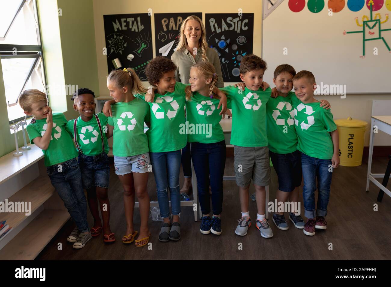 Insegnante di scuola femminile con un gruppo di scolaresche che indossano magliette verdi con un riciclaggio bianco l Foto Stock
