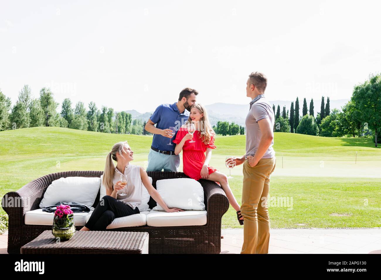Gli amici si godono il vino e parlano sul divano sul campo da golf Foto Stock