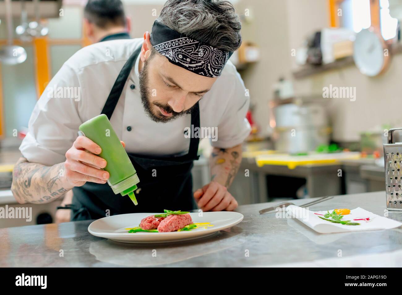 Lo chef prepara piatti di carne cruda in cucina Foto Stock