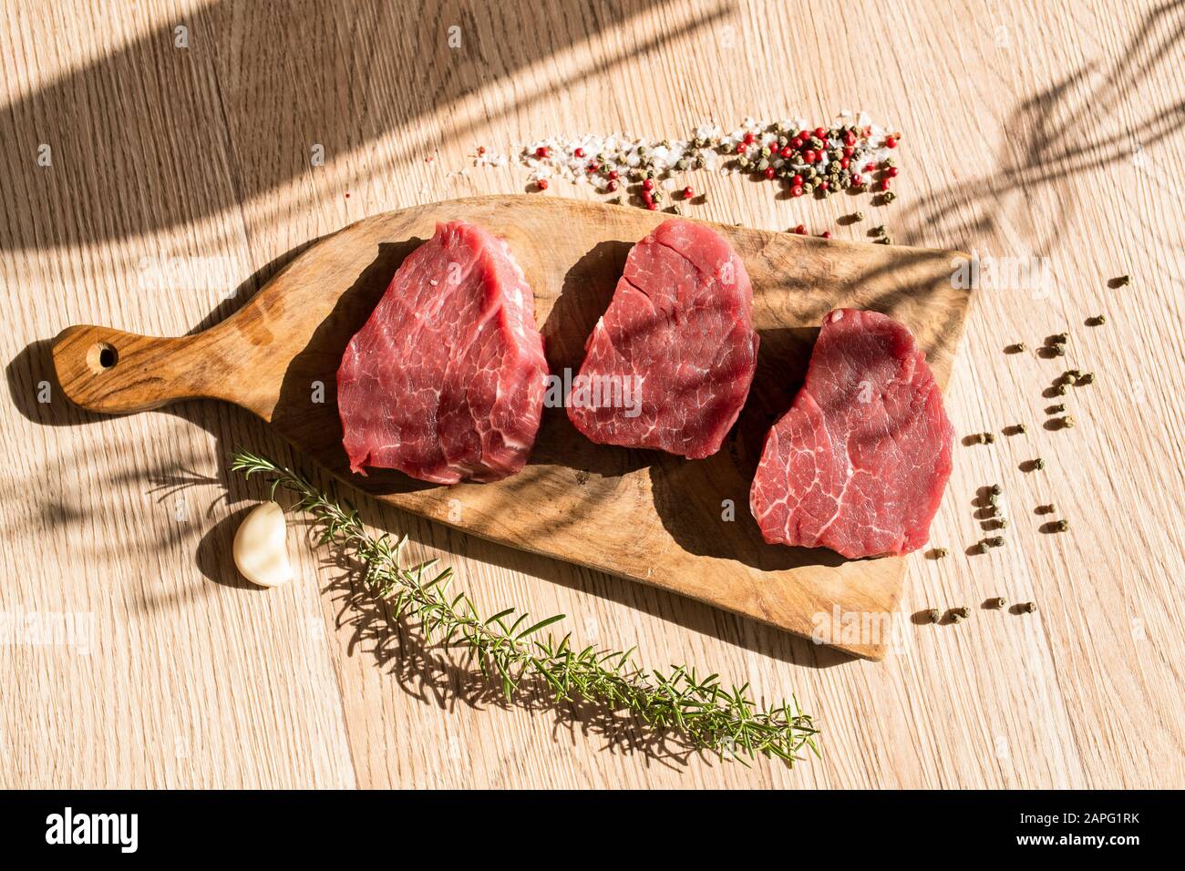 Fette spesse di carne cruda, rosmarino, pepe Foto Stock