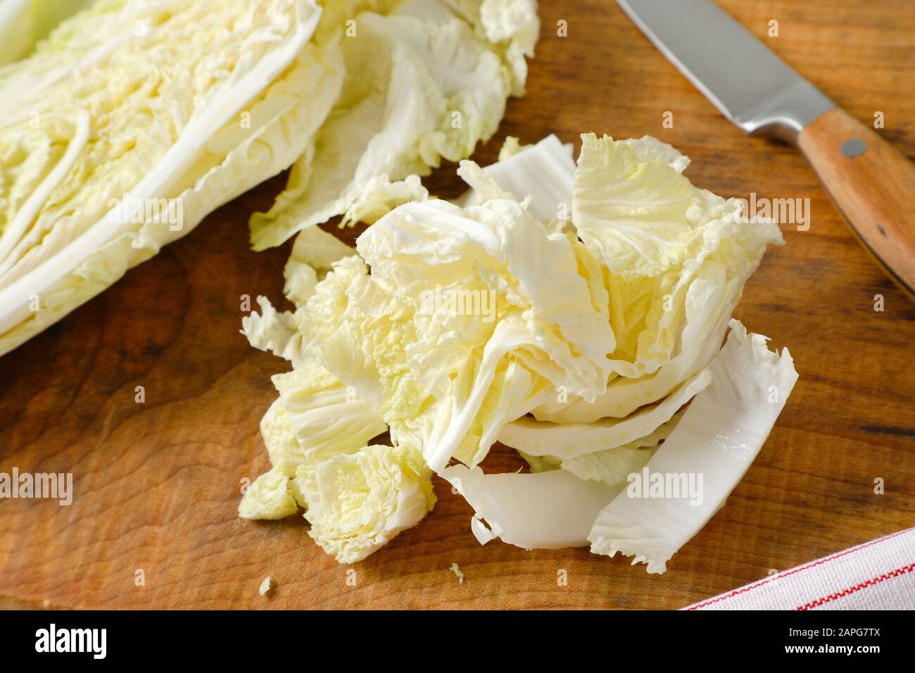 Foglie di cavolo cinesi e coltello da cucina su tagliere di legno Foto Stock