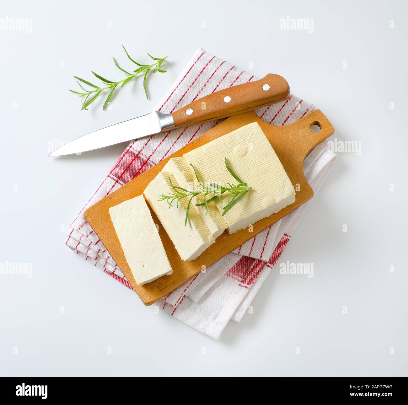 Blocco a fette di cagliata di fagioli freschi (tofu) su tagliere Foto Stock