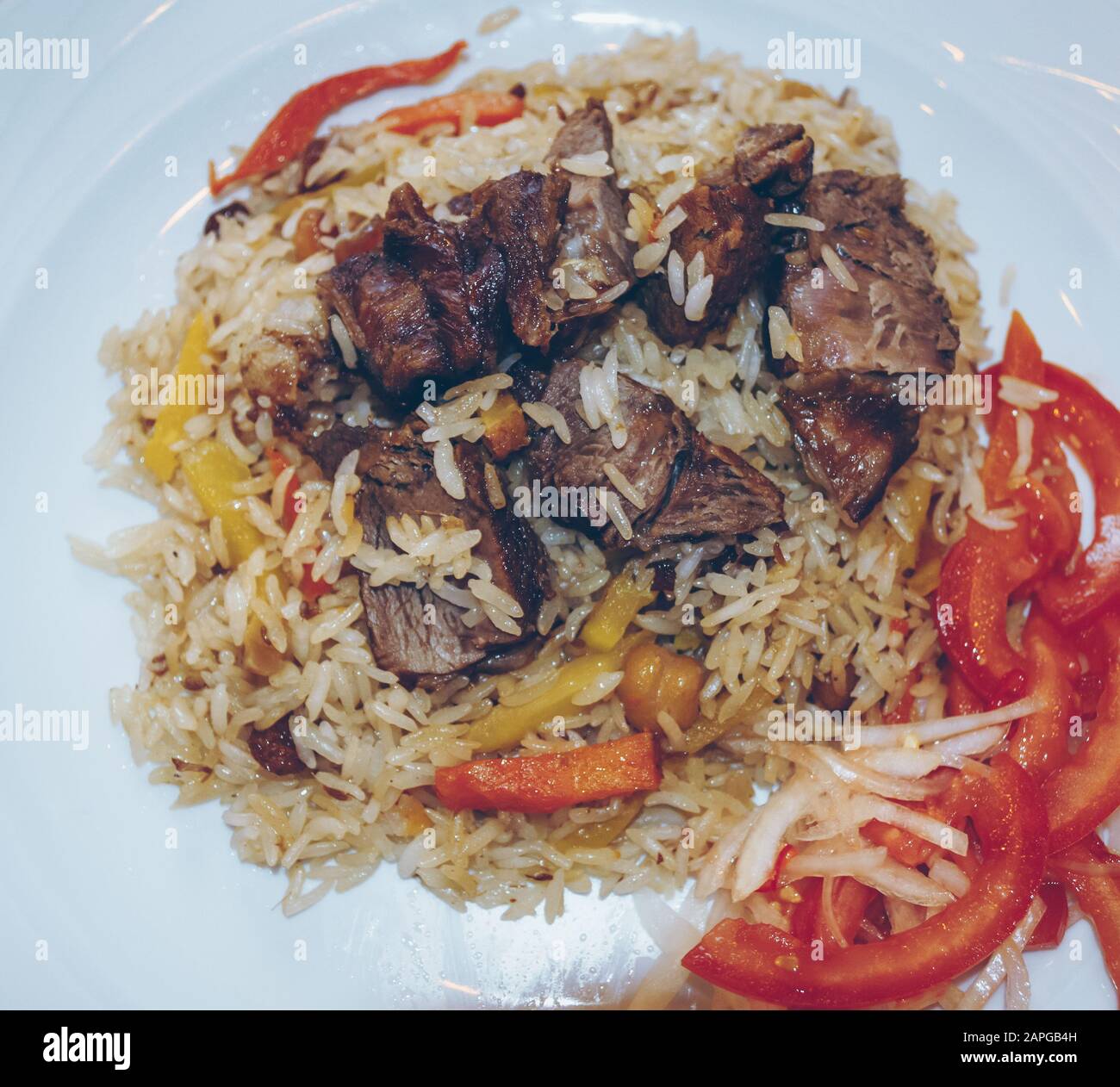 vista ravvicinata del tradizionale pilaf kazakhstan servito con pomodori freschi a dadini e cipolla Foto Stock