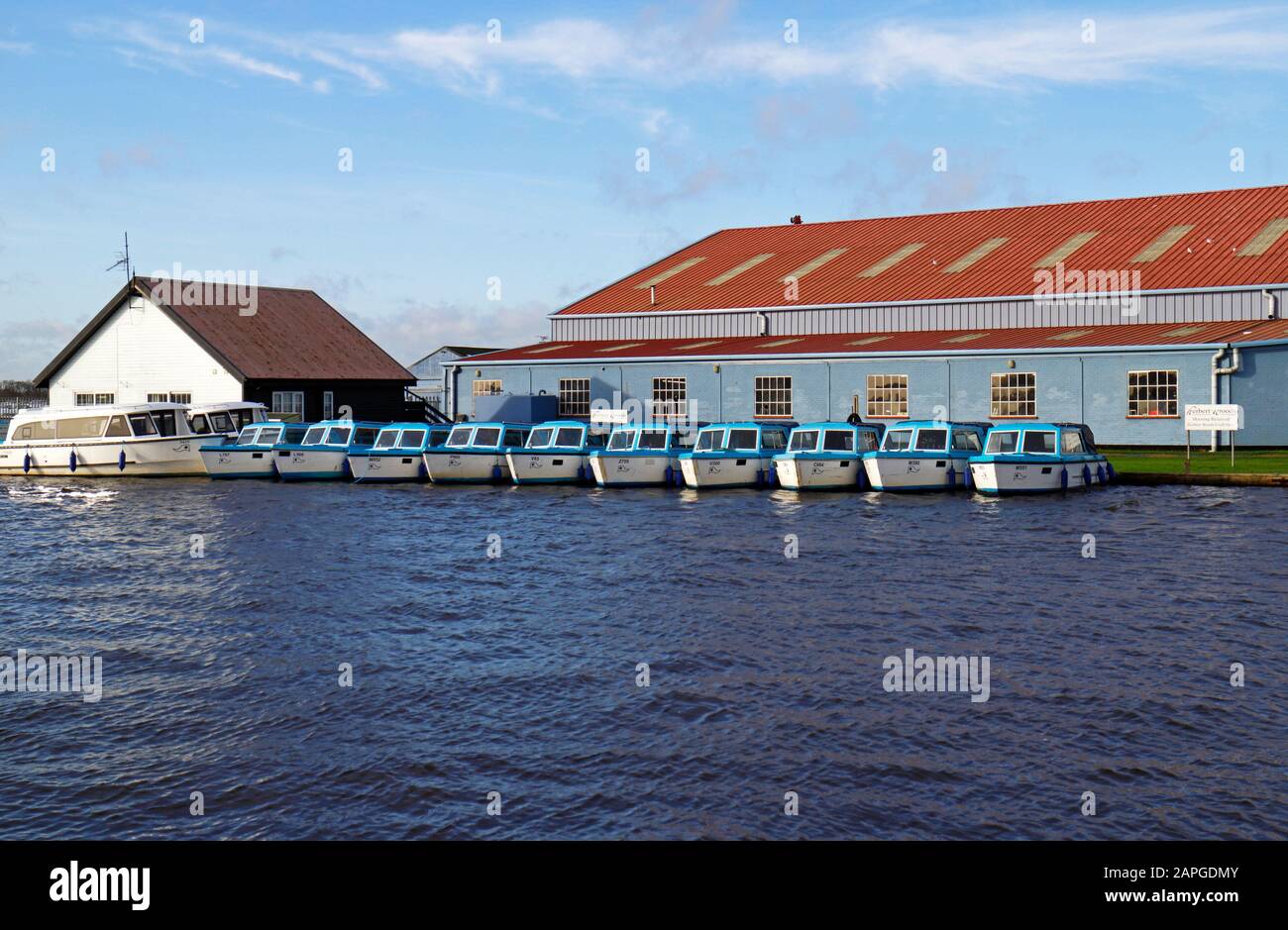 Una fila di dayboats ormeggiati ad un cantiere sul fiume Thurne sul Norfolk Broads dal ponte a Potter Heigham, Norfolk, Inghilterra, Regno Unito Europa. Foto Stock