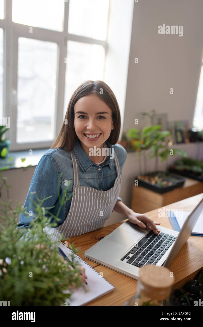 Donna sorridente che lavora con un computer in un negozio di piante Foto Stock