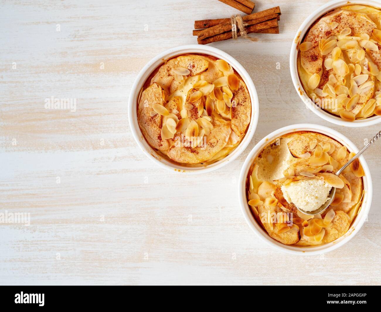 Cheesecake su tavolo di legno bianco in cucina. Delicato dessert al curdo con mele, fiocchi di mandorle Foto Stock