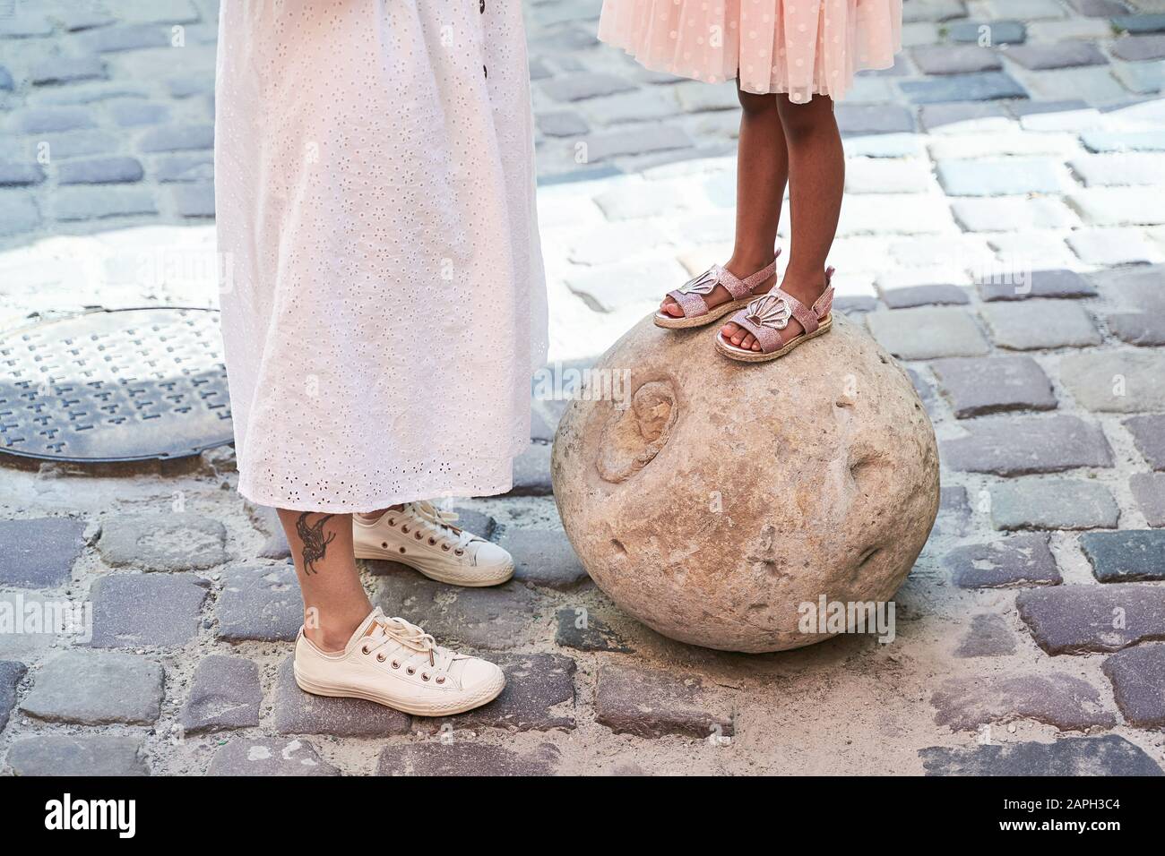 Felice famiglia multietnica dagli Stati Uniti durante il loro viaggio di vacanza in Europa. Madre bianca e la sua adorabile figlia di razza mista in abito rosa in piedi su co Foto Stock