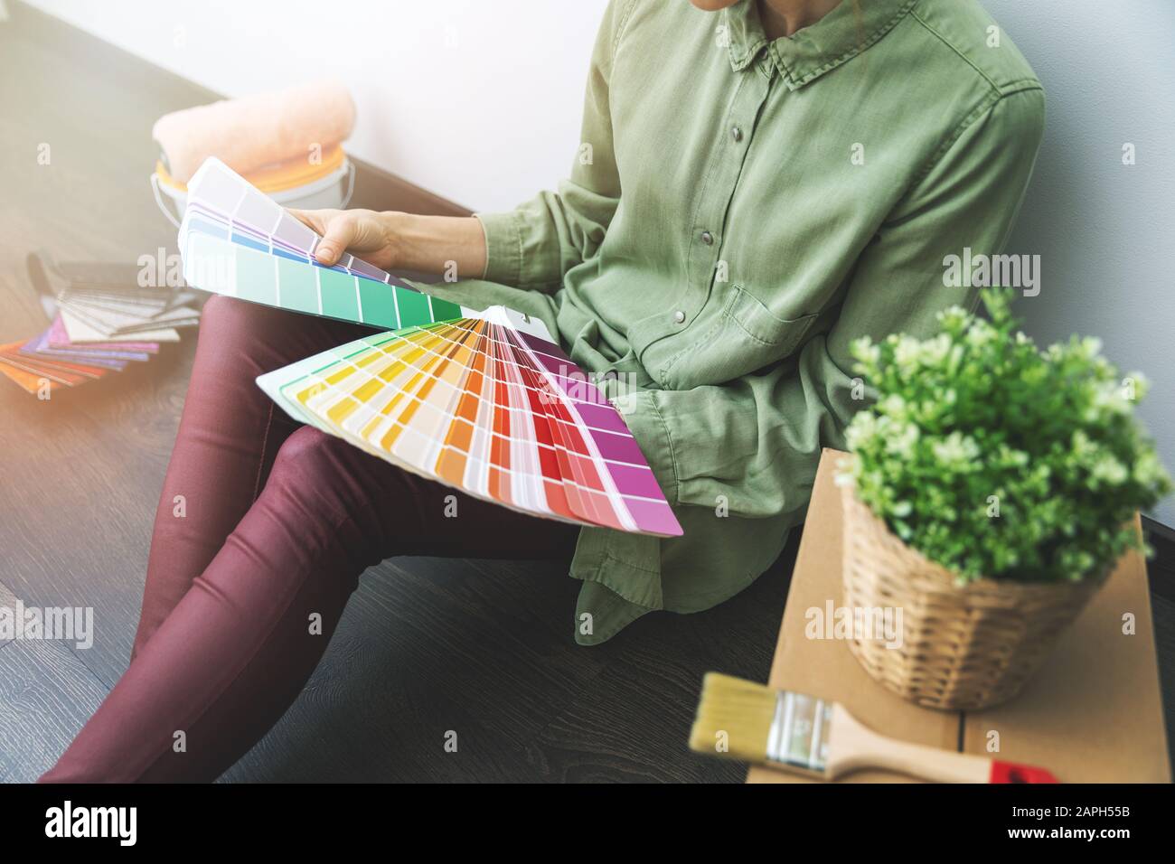donna seduta sul pavimento in camera e la scelta di colore vernice da campioni per il nuovo design degli interni Foto Stock