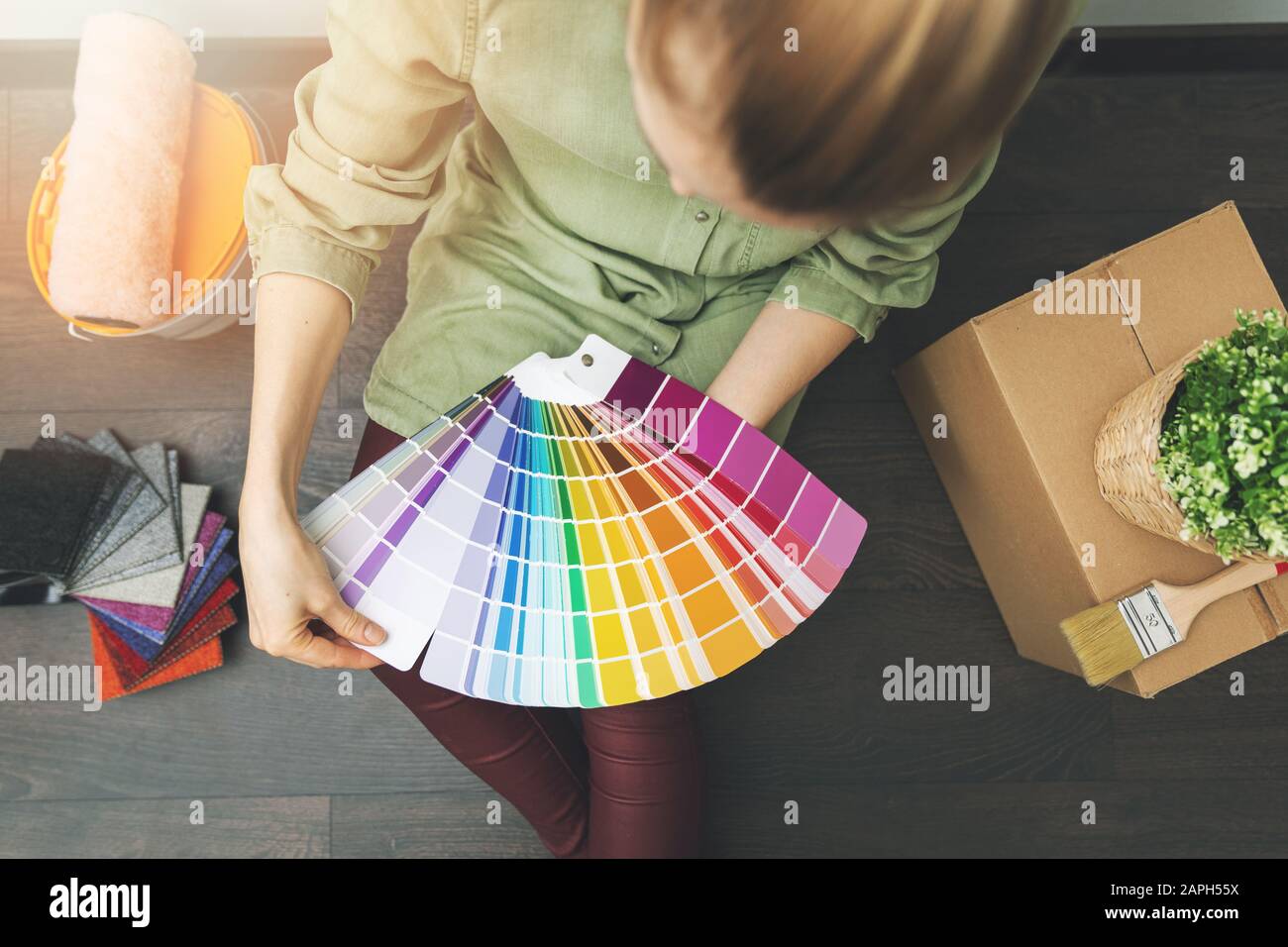 donna seduta sul pavimento in camera e la scelta di colore vernice dal campione per il nuovo design degli interni Foto Stock