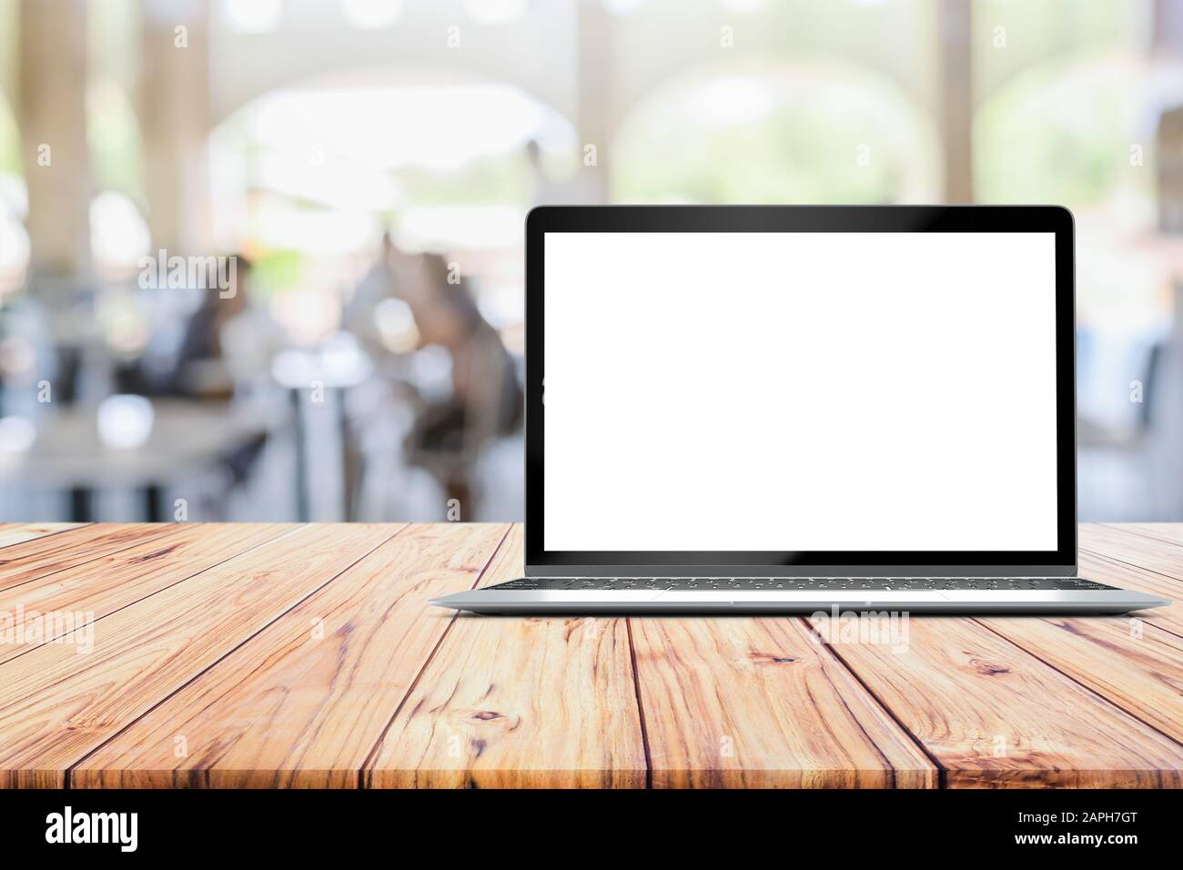 Schermo di simulazione vuoto del laptop collocato su un tavolo di legno sul cliente Defocused al bar del ristorante caffetteria sfocato Foto Stock