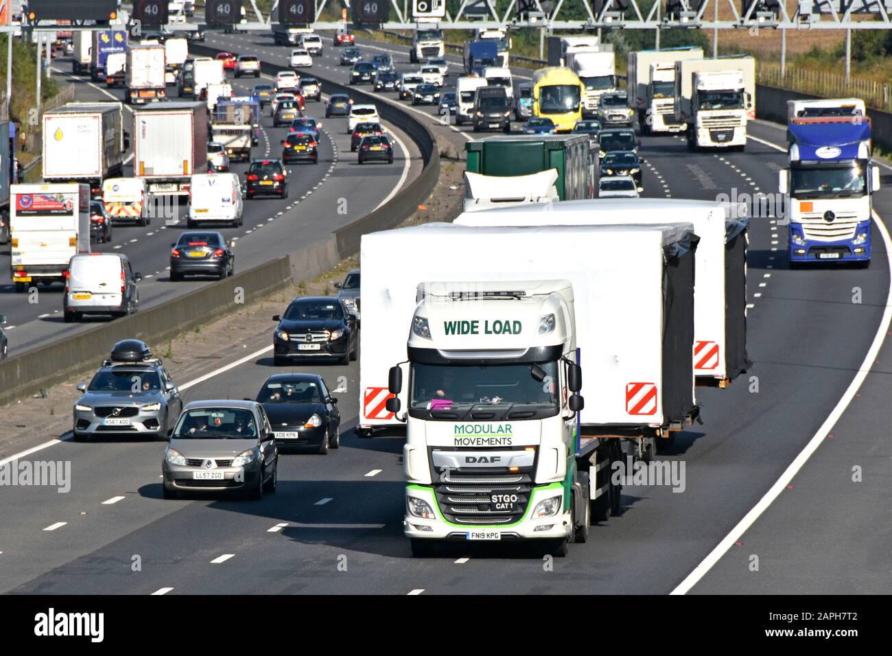 Guardando verso il basso sul traffico lento in retromarcia sulla trafficata autostrada M25 dietro due autocarri caricati con carichi ampi edificio modulare sovradimensionato Inghilterra Regno Unito Foto Stock