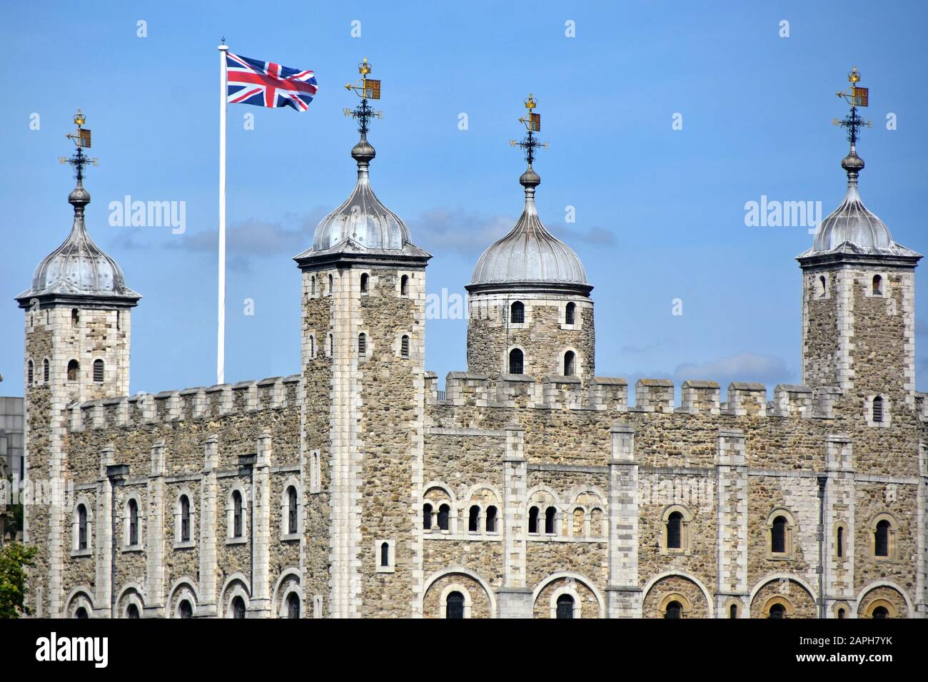 Primo piano di muro di pietra e torretta del tetto del famoso edificio storico della Torre Bianca nella Torre del castello di Londra Union Jack bandiera e meteo bandera Inghilterra UK Foto Stock