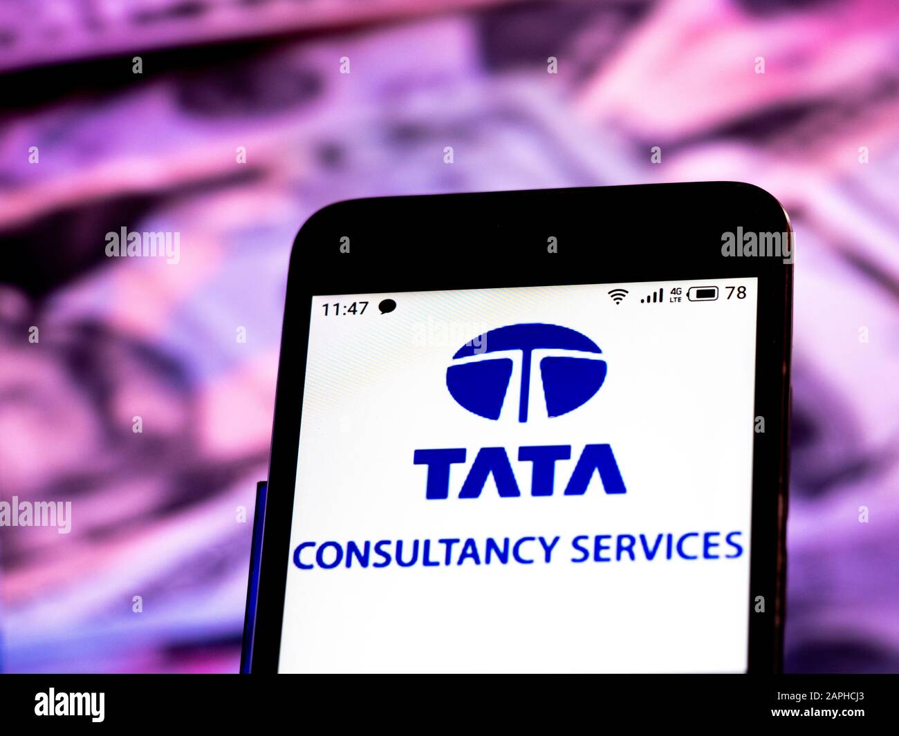 In questa illustrazione della foto, il logo Tata Consultancy Services Limited viene visualizzato su uno smartphone sullo sfondo delle fatture in dollari USA. Foto Stock