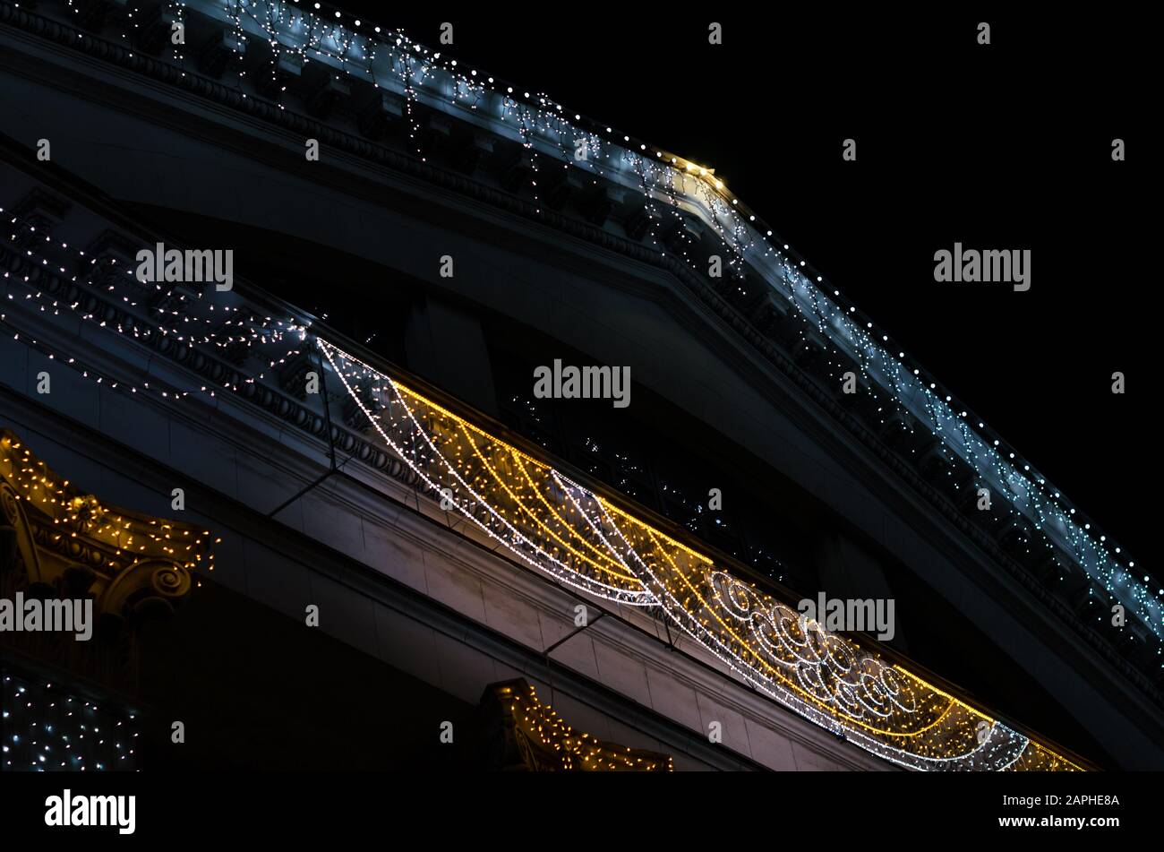 frammento della facciata e del tetto di un edificio d'epoca con decorazione a luci colorate isolato su sfondo nero di notte Foto Stock