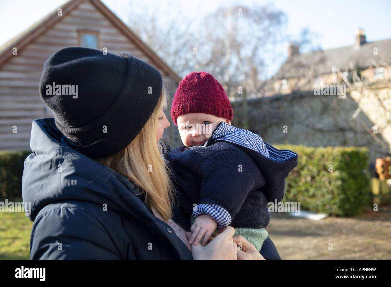 Madre felice che tiene il figlio del bambino nelle sue braccia durante l'inverno Foto Stock