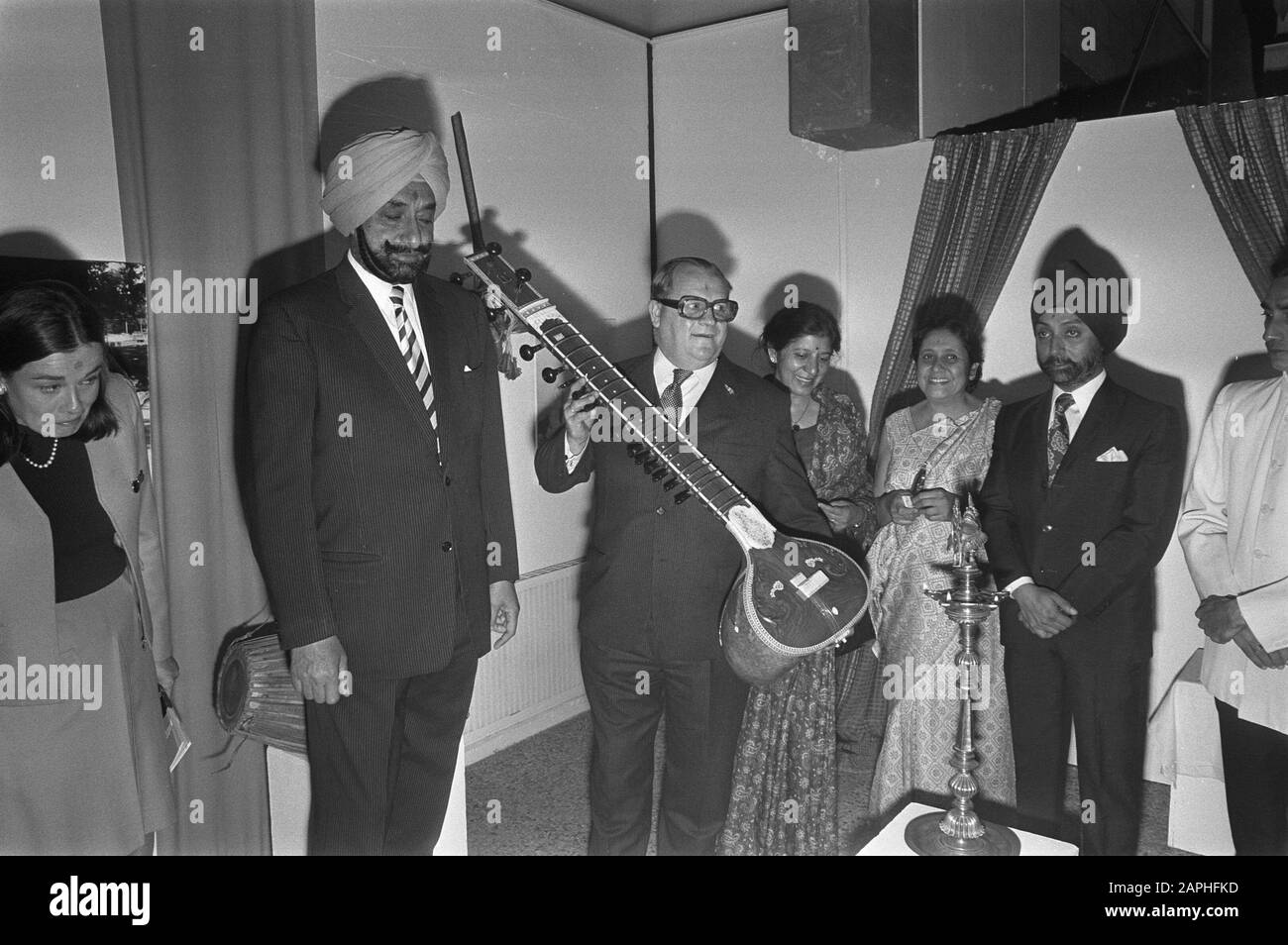 Apertura mostra I Musicmakers dell'India a Madurodam Descrizione: Gli espositori indiani della mostra mostrano uno strumento musicale indiano, il sitar (uomo nel mezzo sconosciuto) - in primo piano una lampada a olio Data: 21 Giugno 1972 luogo: Den Haag, Madurodam, Zuid-Holland Parole Chiave: costume, strumenti musicali, lampade ad olio, aperture, mostre Foto Stock