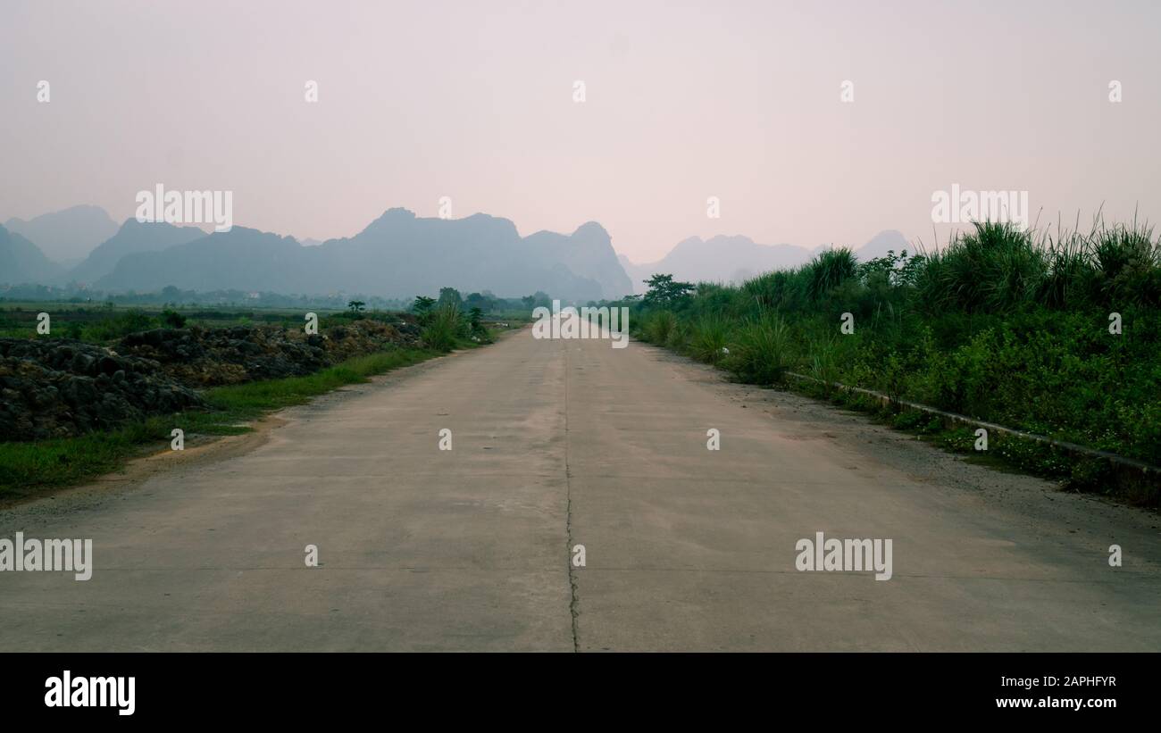 Strada di campagna vuota con montagne carsiche calcaree a Ninh Binh, Vietnam in un giorno torbido. Foto Stock